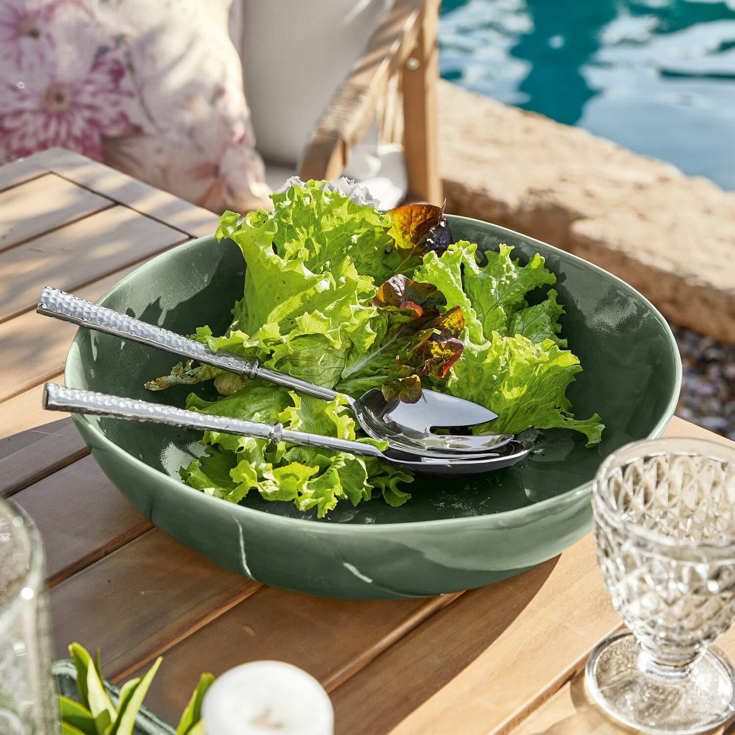 Schaal Calvi Groene keramische kom met sla en zilveren bestek op houten tafel buiten