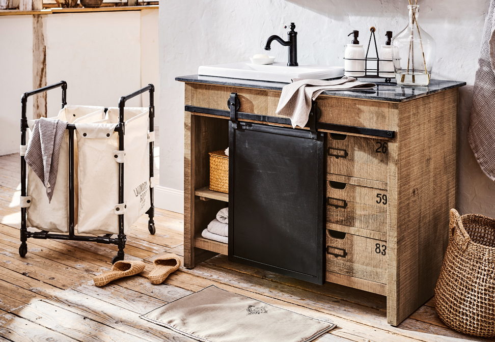 Industriële badkamer met houten kast, zwarte metalen lade en witte wastafel op stenen blad