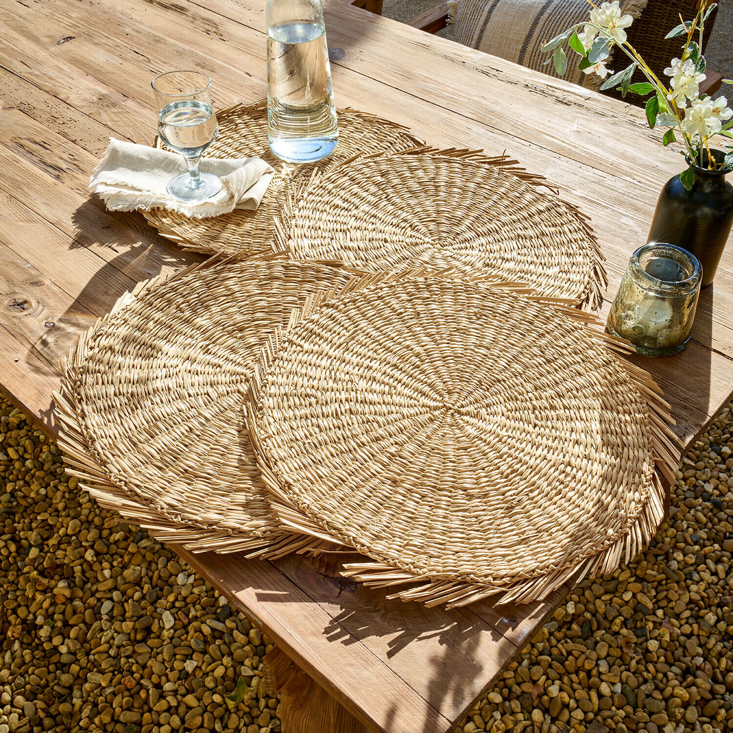 Ronde placemats van natuurlijk gevlochten materiaal op houten tafel buiten