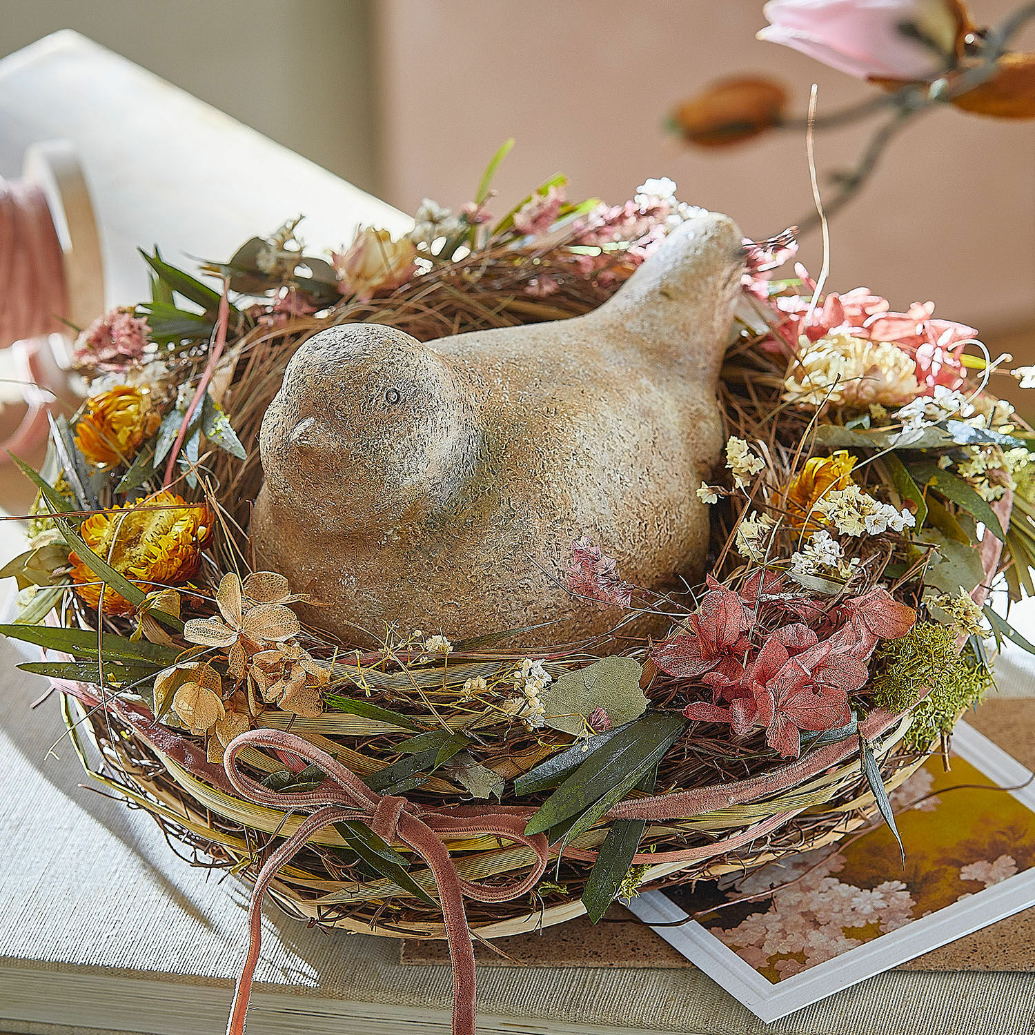 Siervogeltje Nafisah Decoratieve stenen vogel in een wilgennest met gedroogde bloemen op tafel