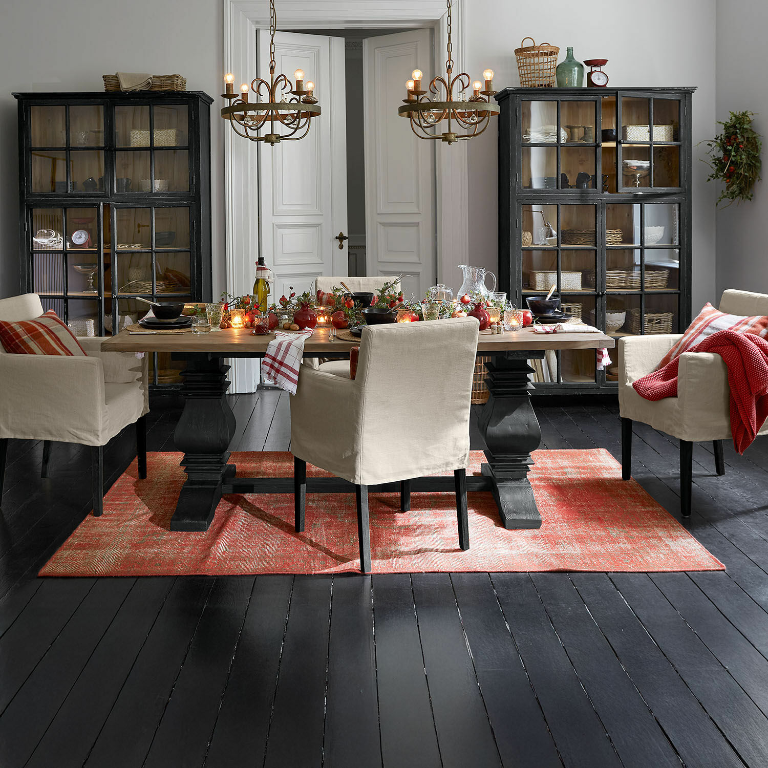 Eetkamer met houten tafel, beige stoelen en rood vloerkleed op zwarte vloer, feestelijke tafelversiering