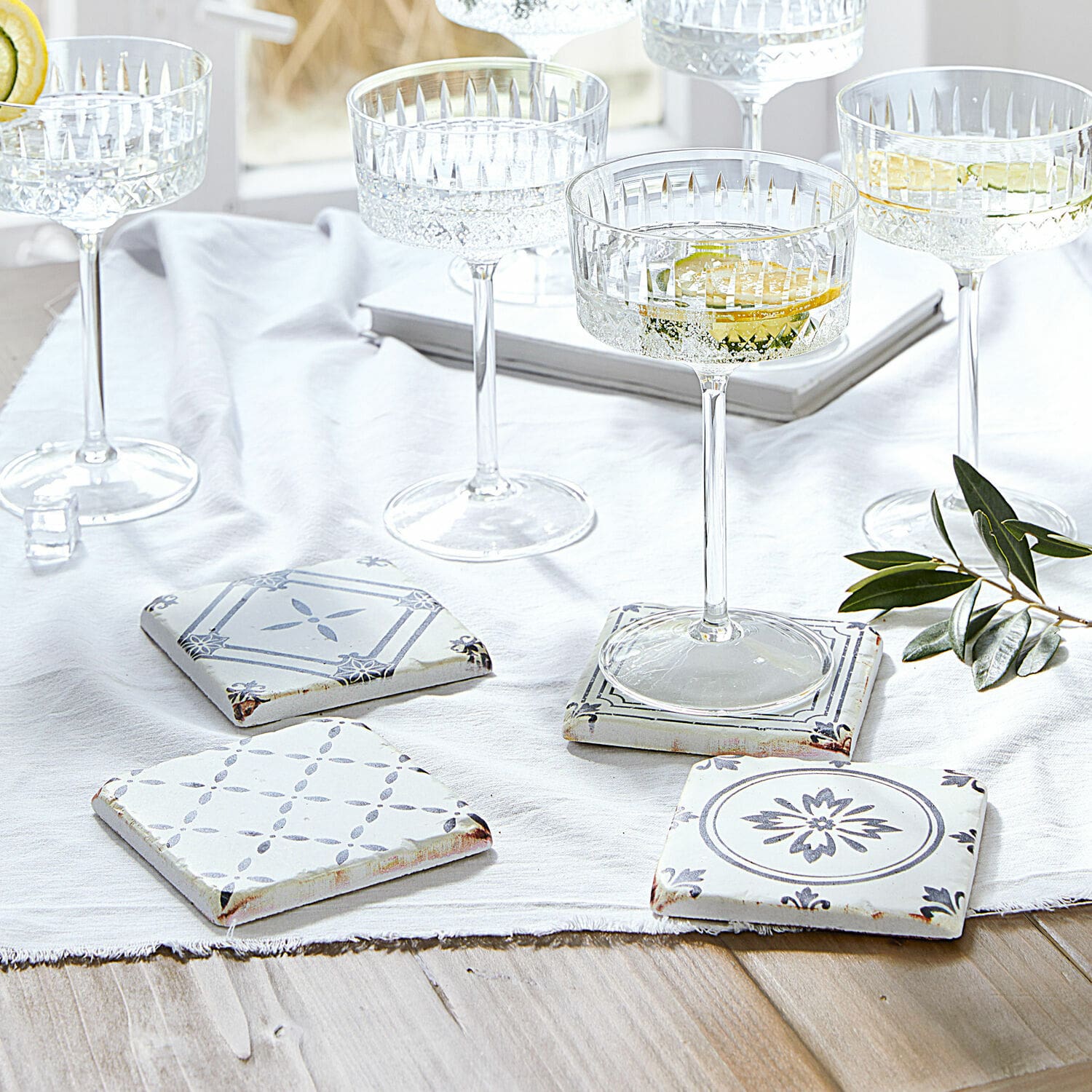 Onderzetter set van 4 Emma Set keramische onderzetters in wit en grijs met patroon op lichte houten tafel met glazen