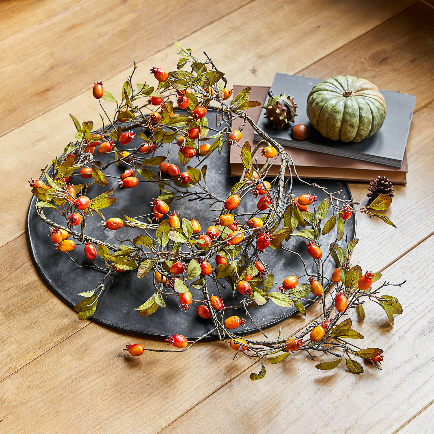 Decoratieve krans met rode en oranje bessen op zwart dienblad op houten tafel