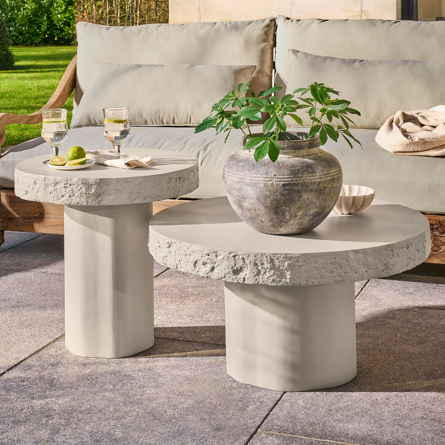Salontafel set van 2 Tivoliq Set van twee ronde bijzettafels van lichtgrijs beton op terras met plant en drankjes