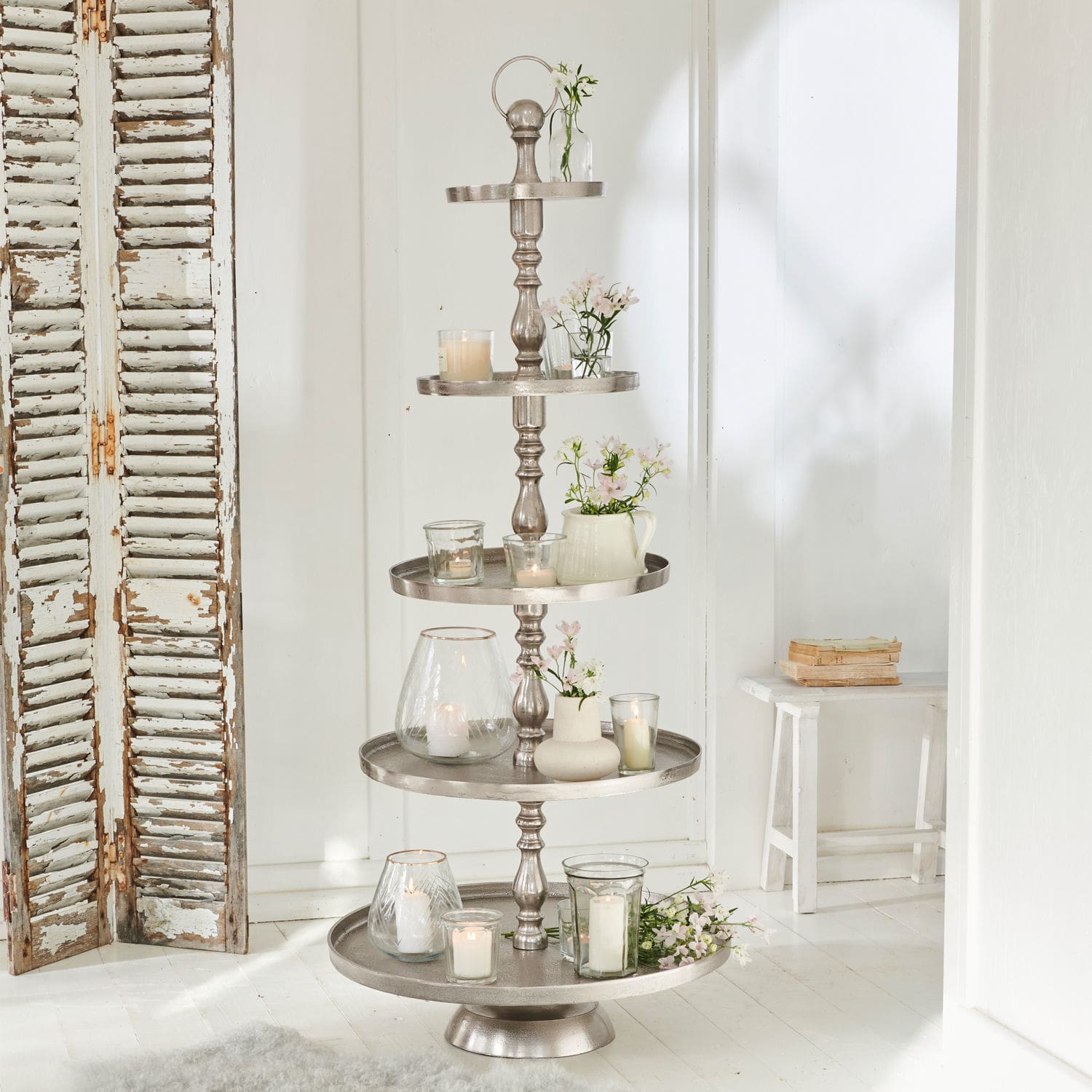 Etagère Magonie Vijfdelige zilverkleurige metalen etagère met kaarsen en witte bloemen als decoratie