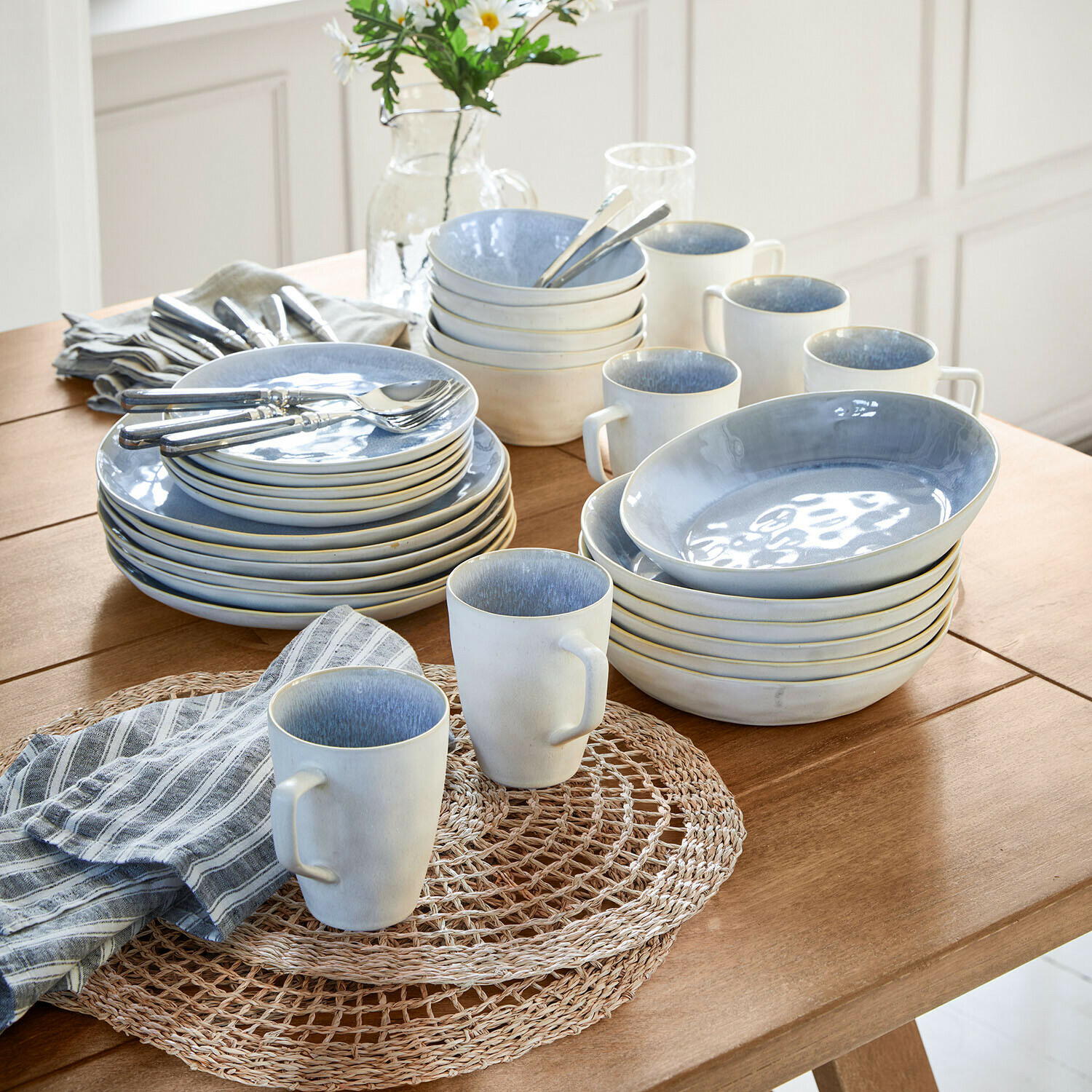 Blauw-wit keramisch servies op houten tafel met gestreepte stoffen servetten