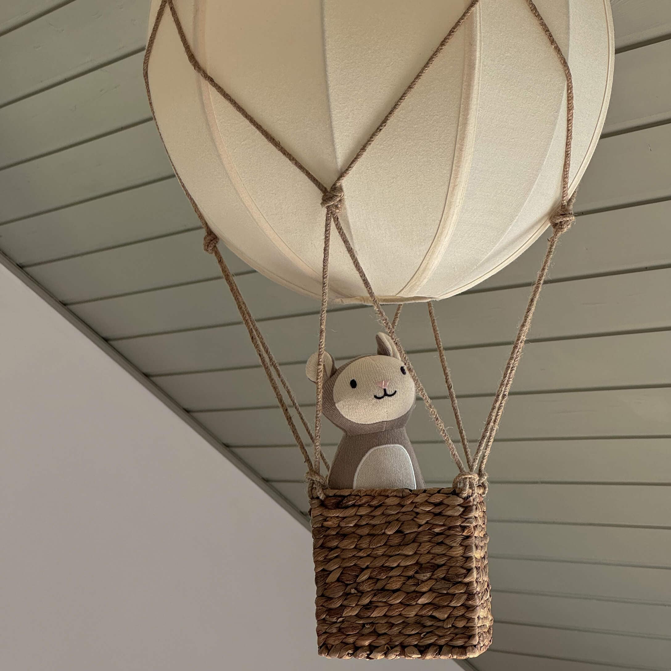 Decoratieve hangende ballon met rieten mand en beige knuffeldier in neutrale tinten