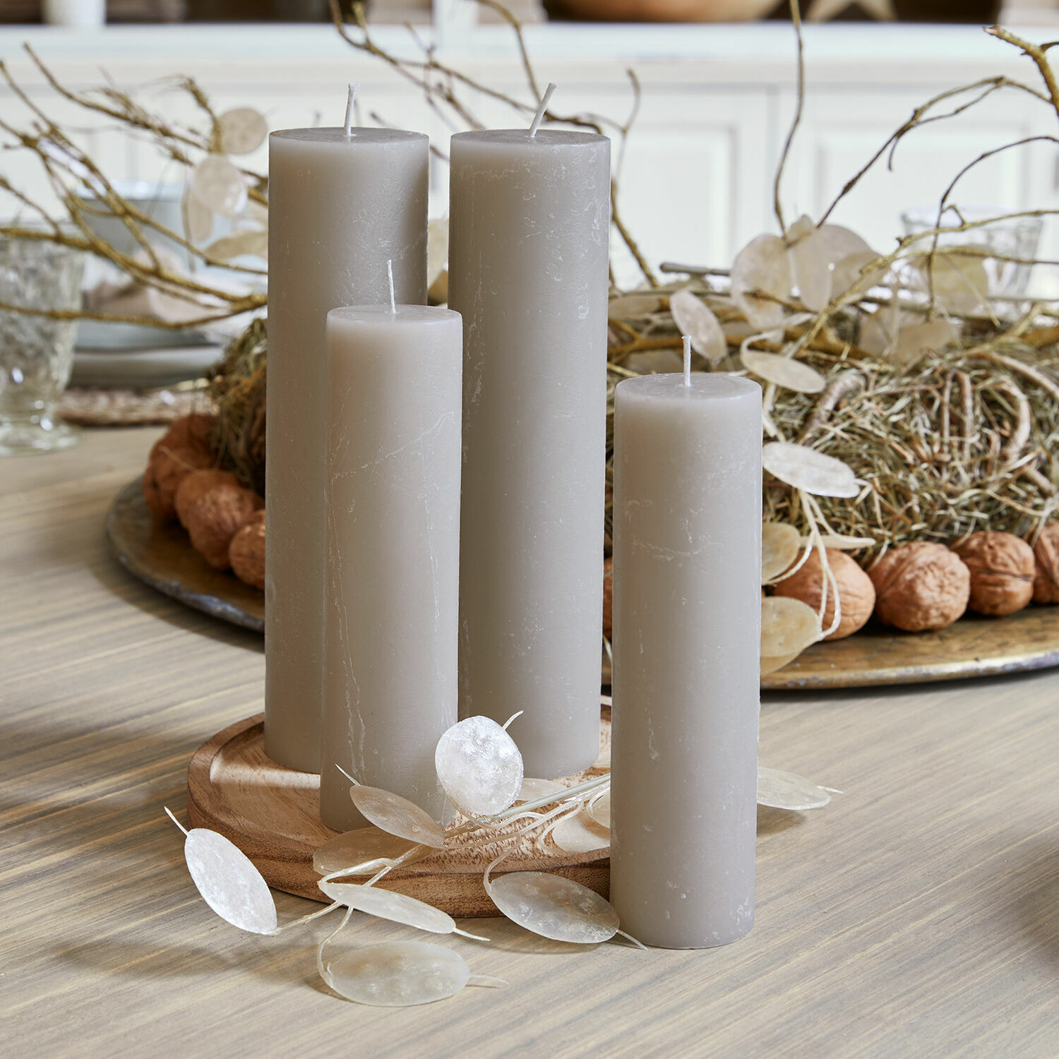 Set van vier grijze waskaarsen op houten schaal, natuurlijke tafeldecoratie met takken