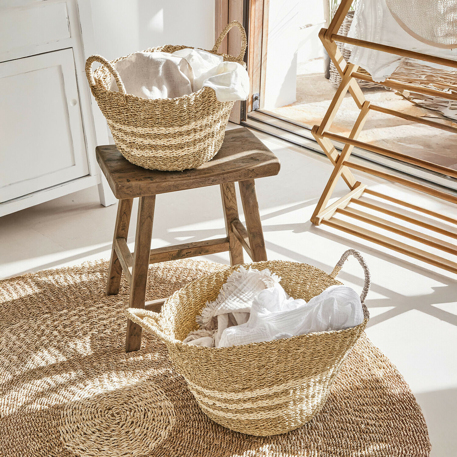 Natuurlijke zeegrasmanden met witte stoffen op ronde mat in lichte kamer
