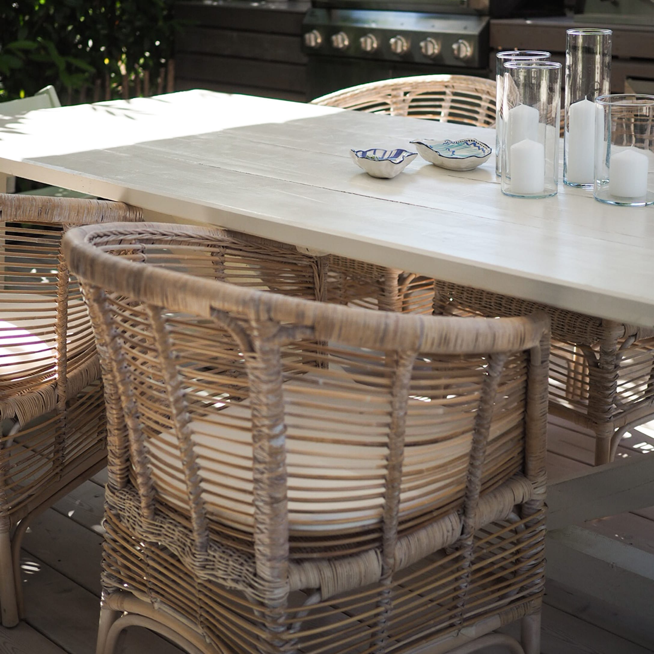 Lichte houten tuintafel met rotan stoelen en decoratieve kaarsen op het terras