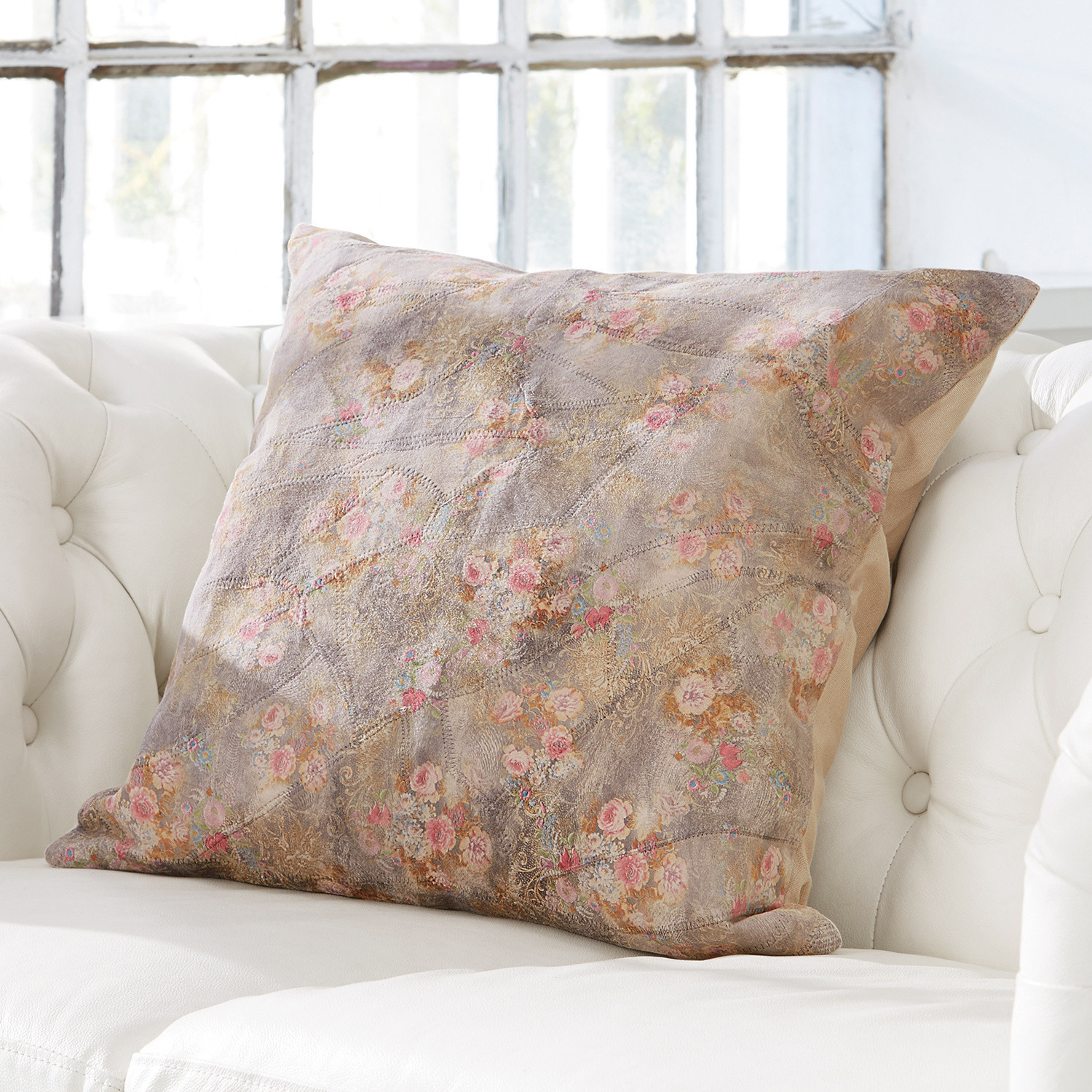 Decoratief kussen met pastelbloemenpatroon op lichte stof op een witte bank