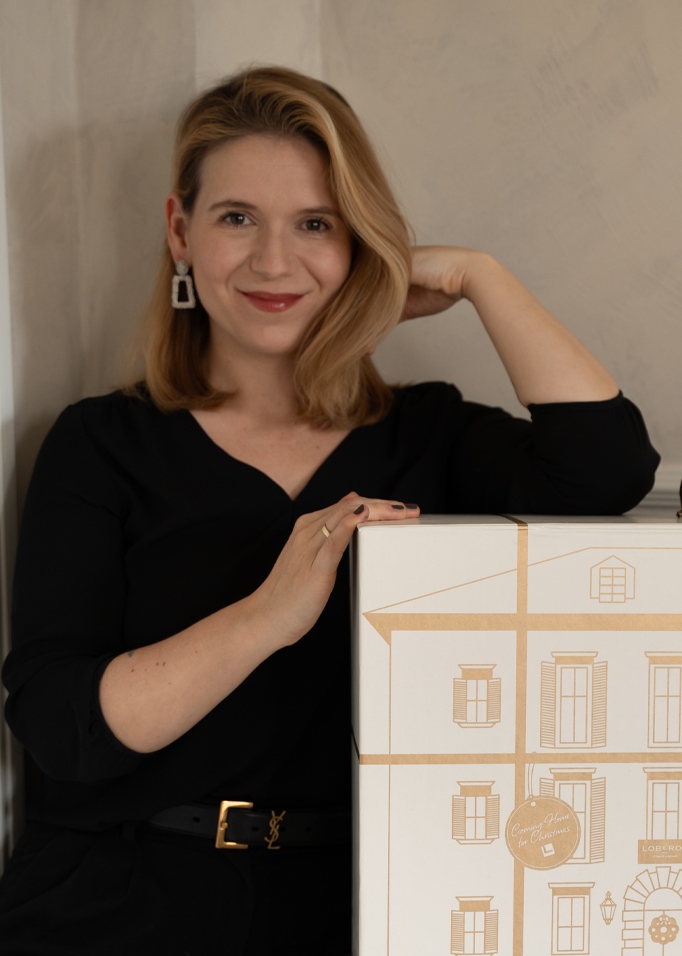 Vrouw in zwarte blouse met geschenkdoos bedrukt met huis, kerstcadeau