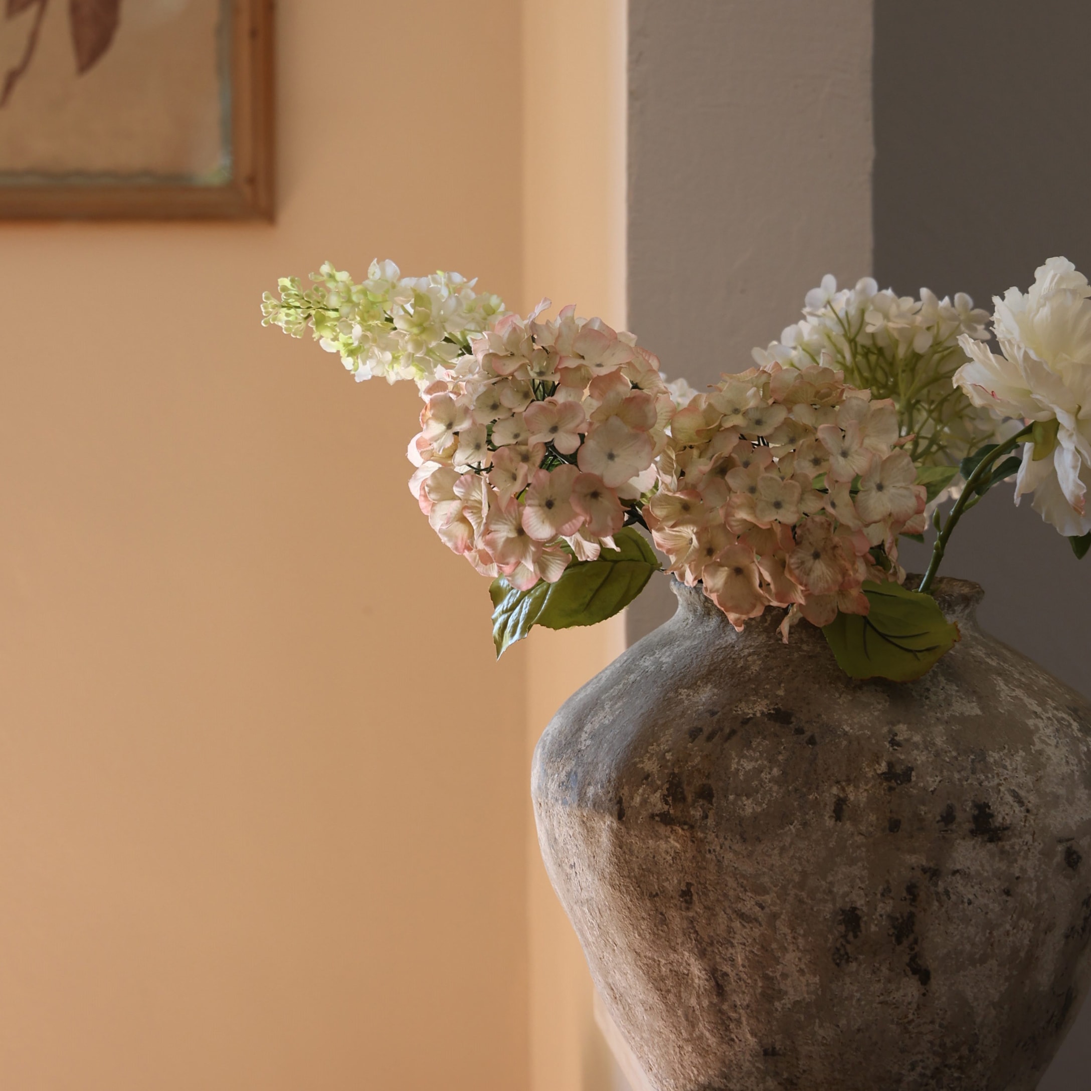 Grote rustieke stenen vaas met delicate bloemen in pasteltinten voor interieurdecoratie