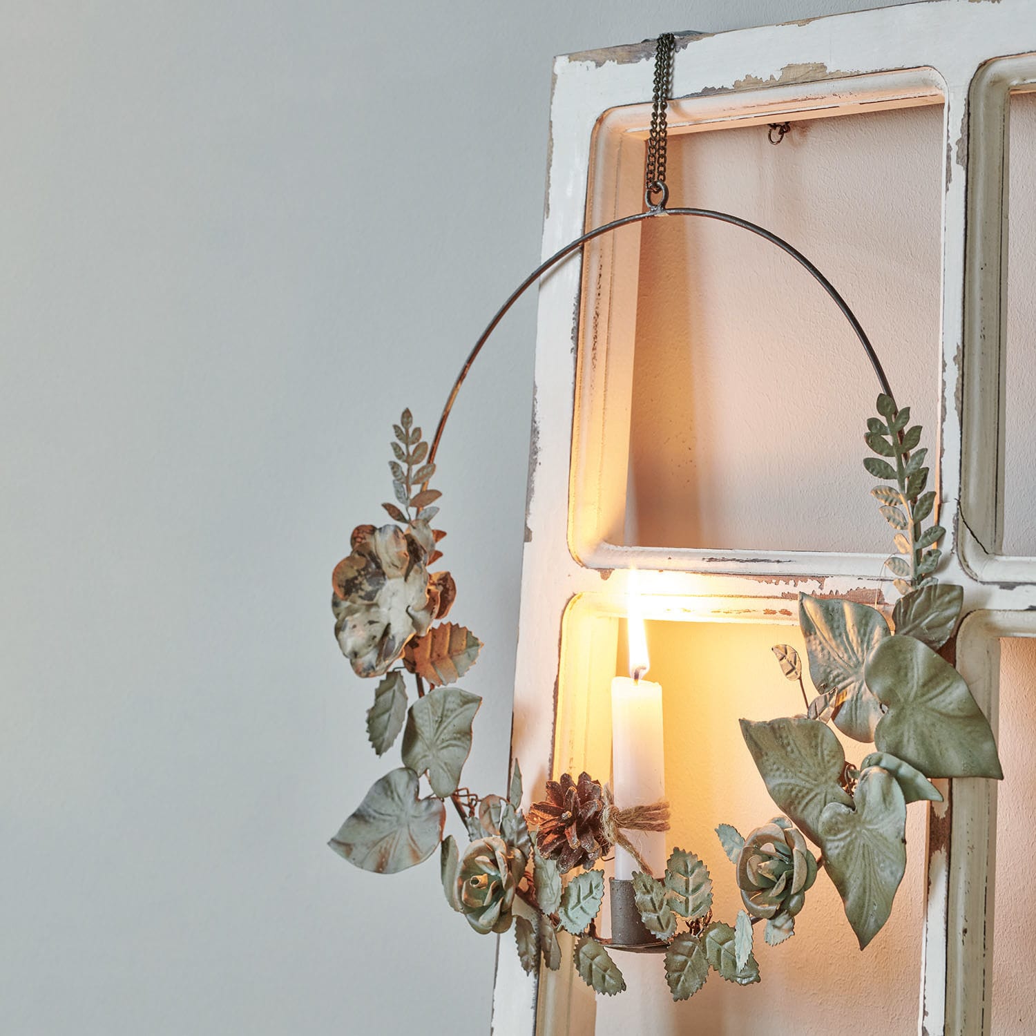 Kaarshouder Néville Metalen krans met groene bladeren en bloemen, witte decoratieve kaars brandt