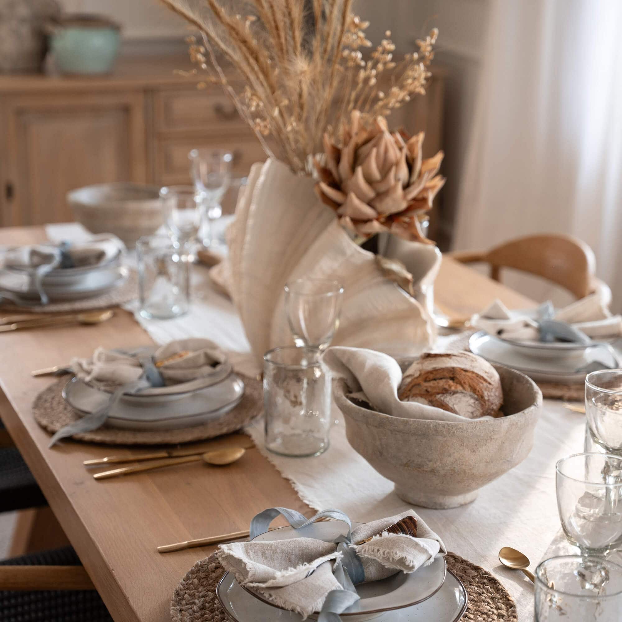 Rustieke eettafel met keramische borden, natuurlijke tafelloper en gedroogde bloemen als decoratie