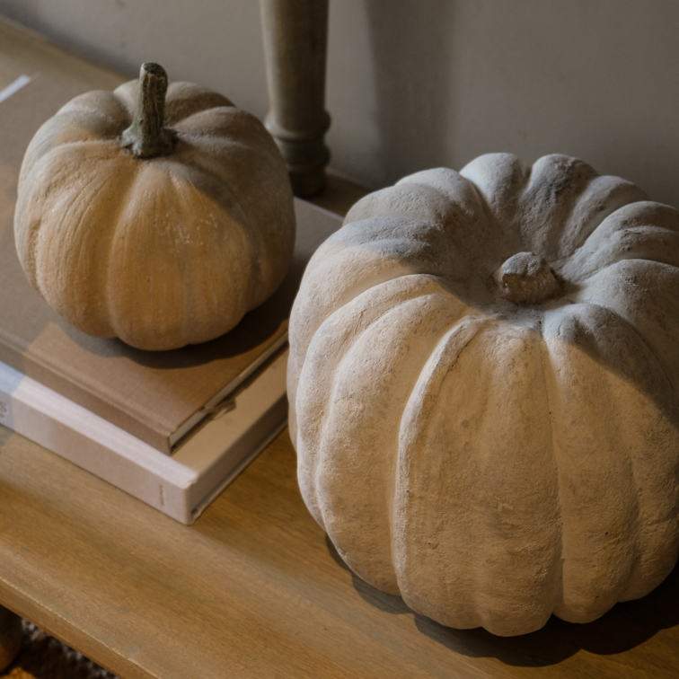 Decoratieve betonnen pompoenen in natuurlijke tinten op houten tafel, herfstinterieurdecoratie