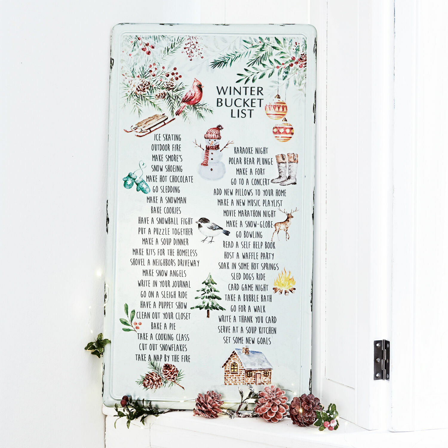 Witte metalen bord met winter bucketlist en feestelijke illustraties als seizoensdecoratie