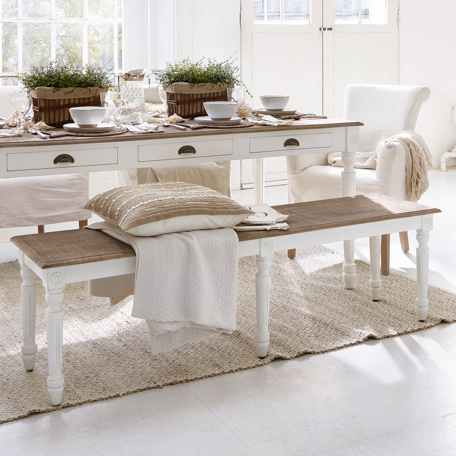 Bankje Helsinquia Witte houten bank met bruin blad in lichte woonkamer met decoratie en textiel