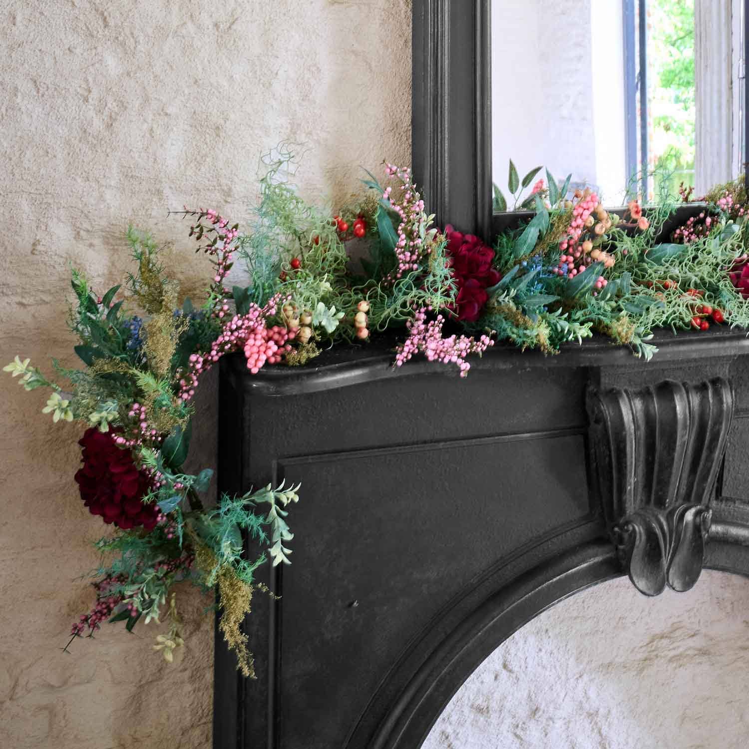 Decoratieve krans met rode en roze bessen en groen blad op een zwarte open haard