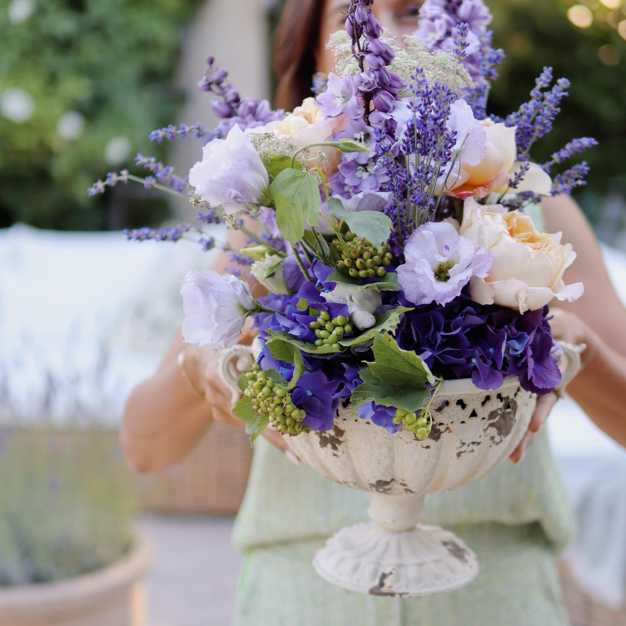 Boeket van paarse en crèmekleurige bloemen in een decoratieve witte keramische vaas op voet