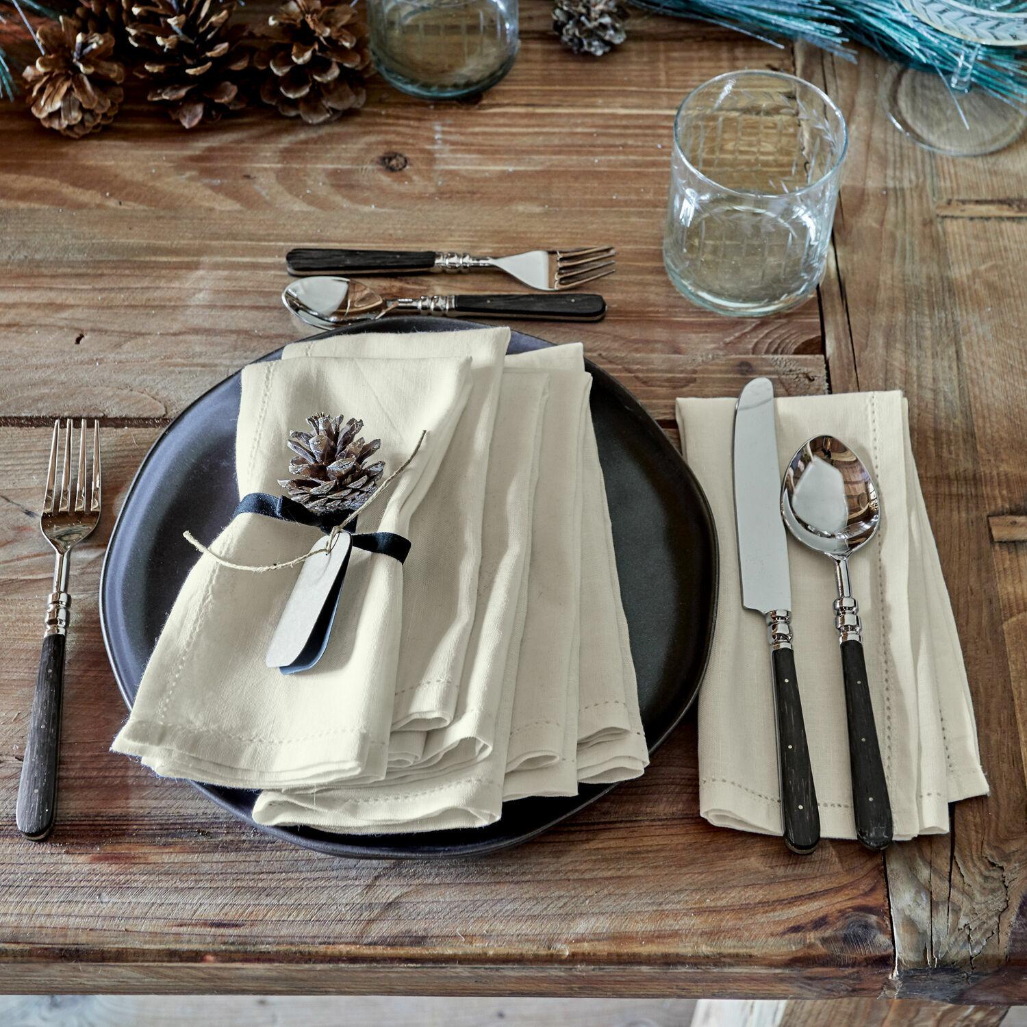 Rustieke houten tafel met zwart bord, crèmekleurige linnen servetten en bestek met zwarte handvatten