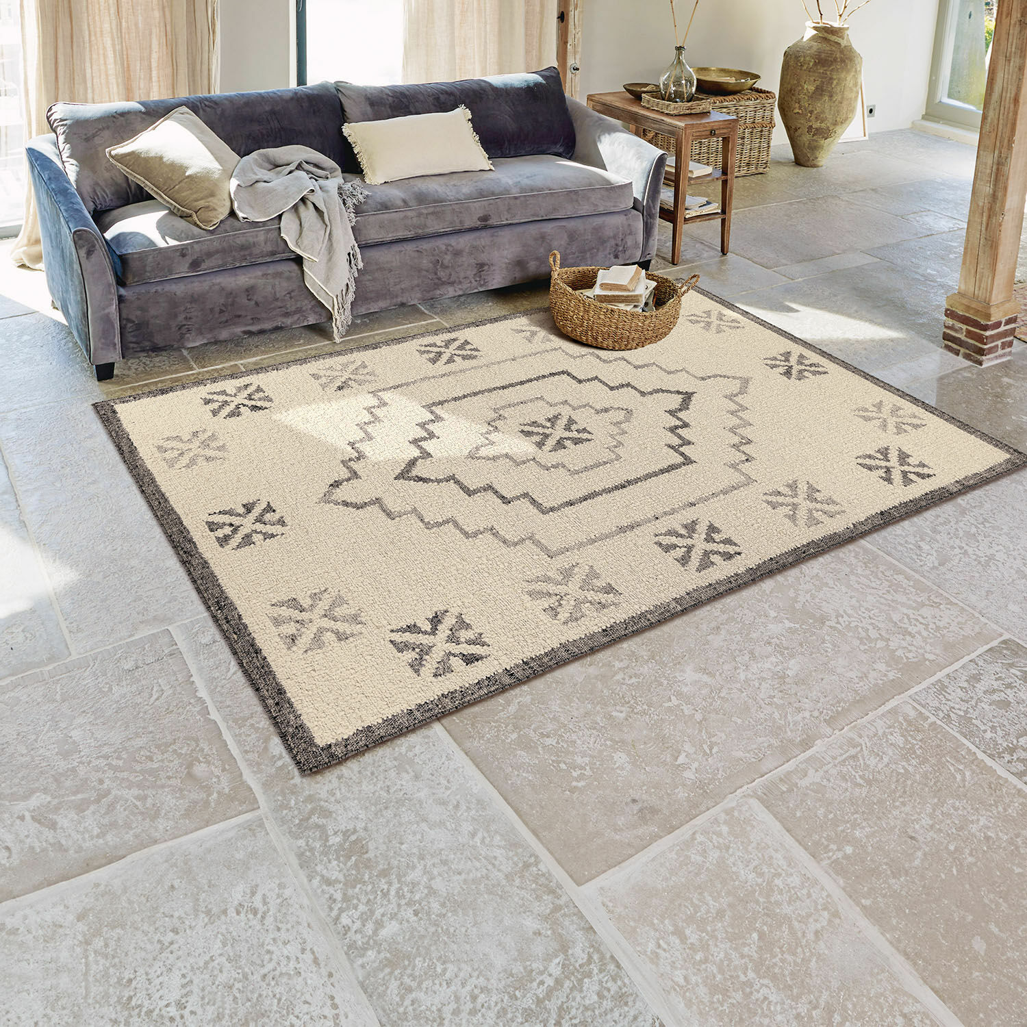 Beige vloerkleed met grijs geometrisch patroon op stenen vloer in lichte woonkamer