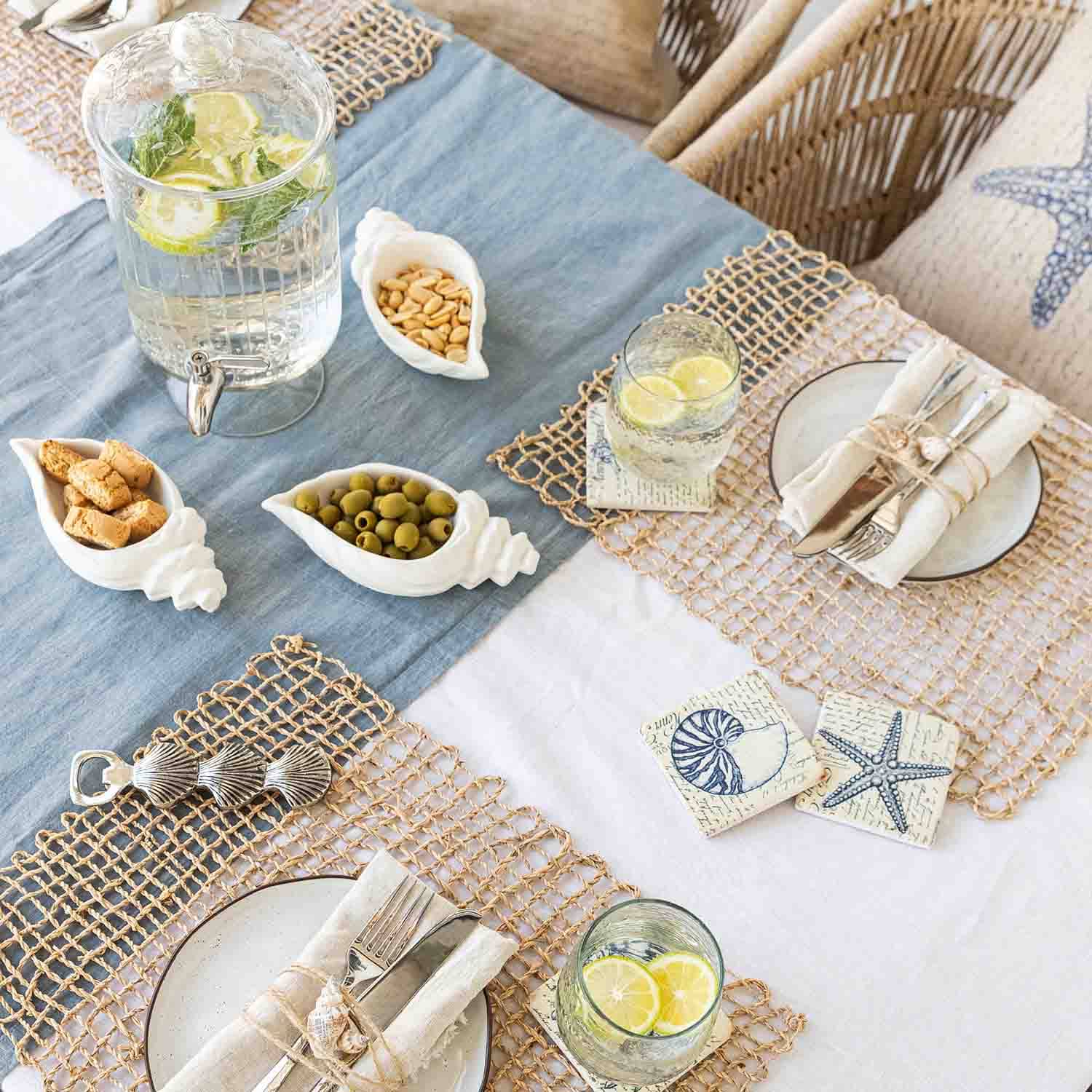 Zomerse tafel met maritieme decoratie, witte keramische schelpvormige schaaltjes met snacks en limonade