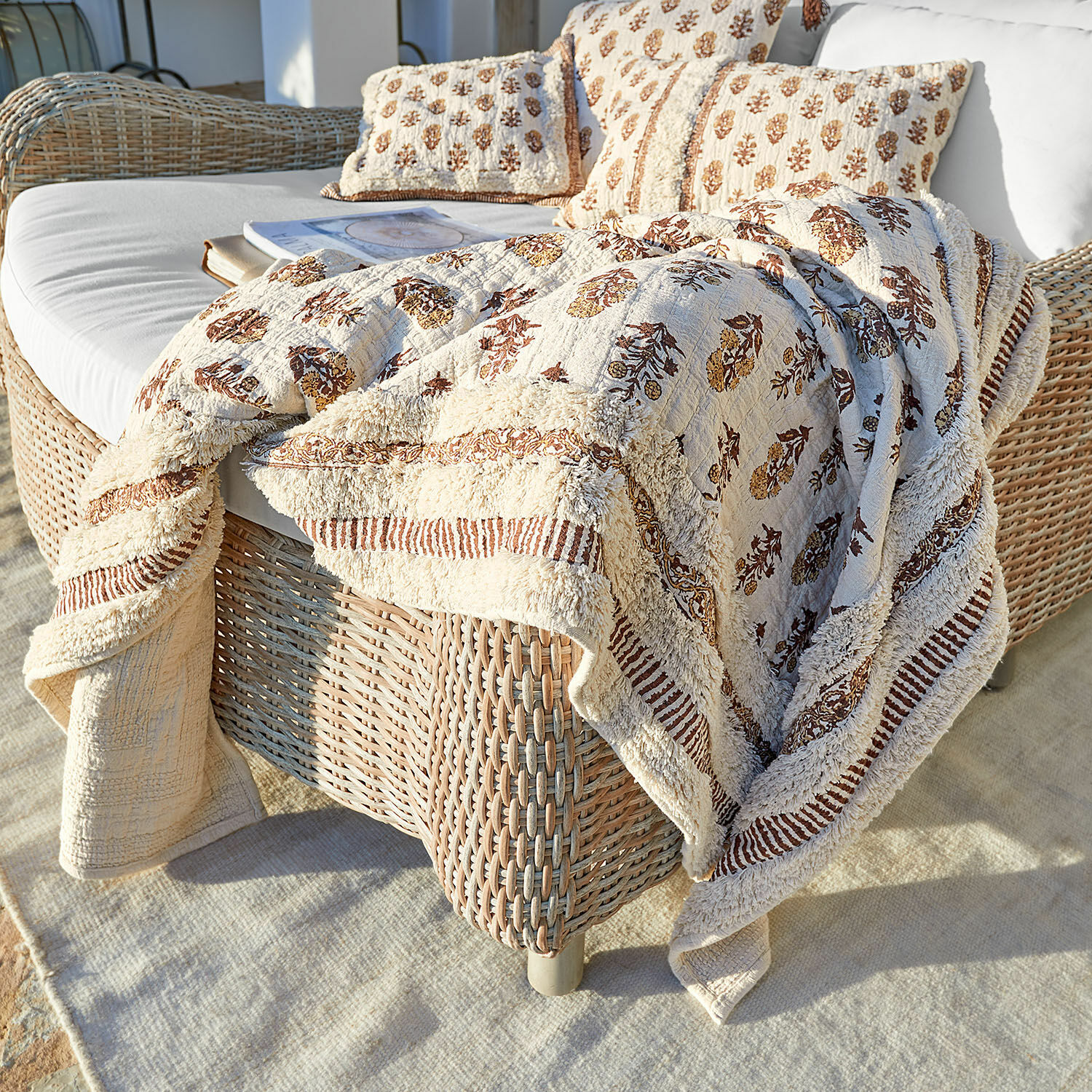Plaid Arsalan Beige katoenen deken en kussens met bruin patroon op rotan bank op terras