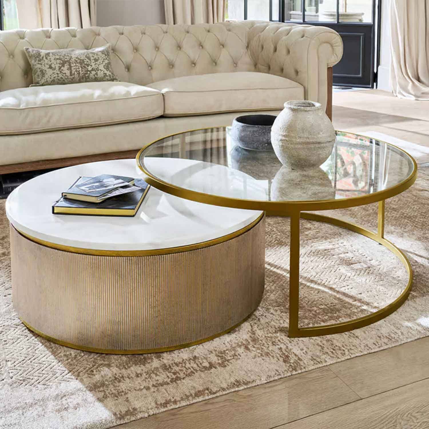 Set van twee salontafels met wit marmeren en glazen blad en gouden frame in woonkamer