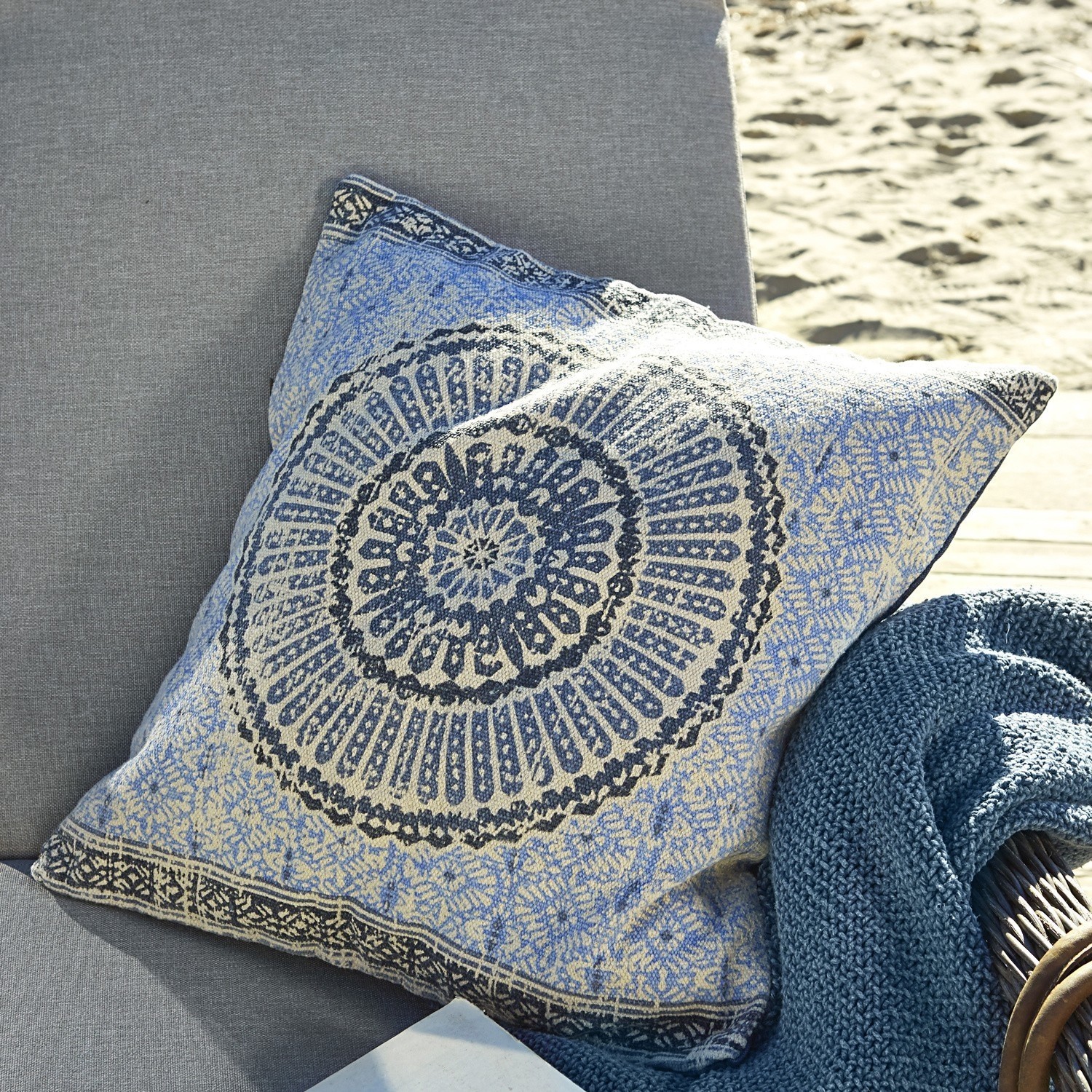 Decoratief katoenen kussen in blauw-beige met oosters patroon op een grijze bank