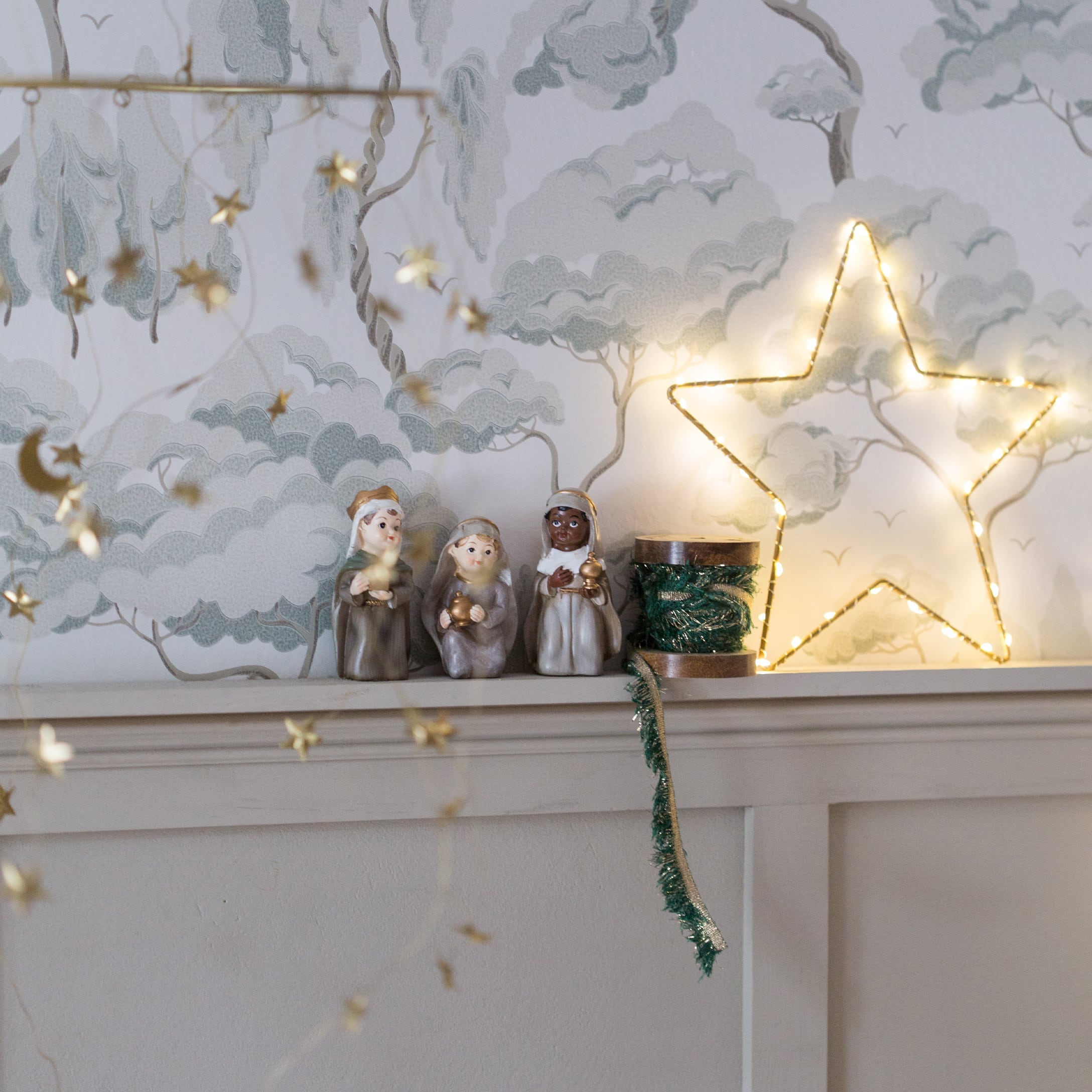 Kerstdecoratie met drie Wijzen-figuren en verlichte ster op witte plank