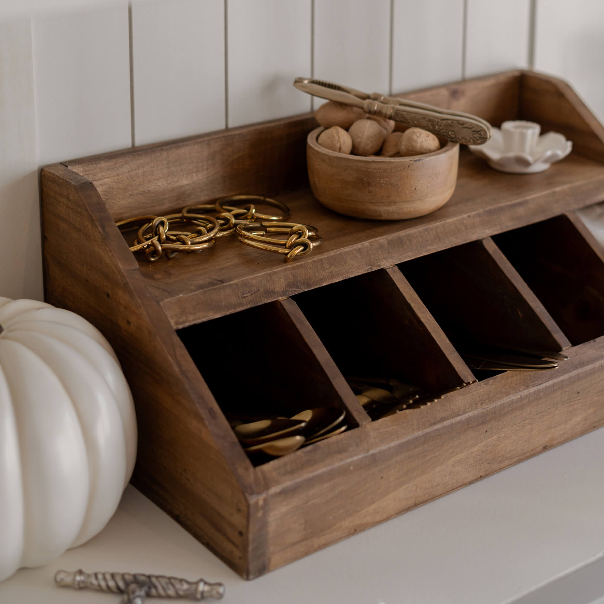 Houten organizer met vakken en kom met noten op lichte ondergrond voor het opbergen van kleine spullen