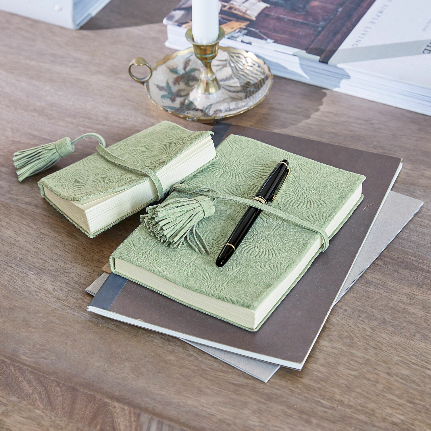 Groen notitieboek van zacht leer met reliëf en kwastje op houten tafel met zwarte pen