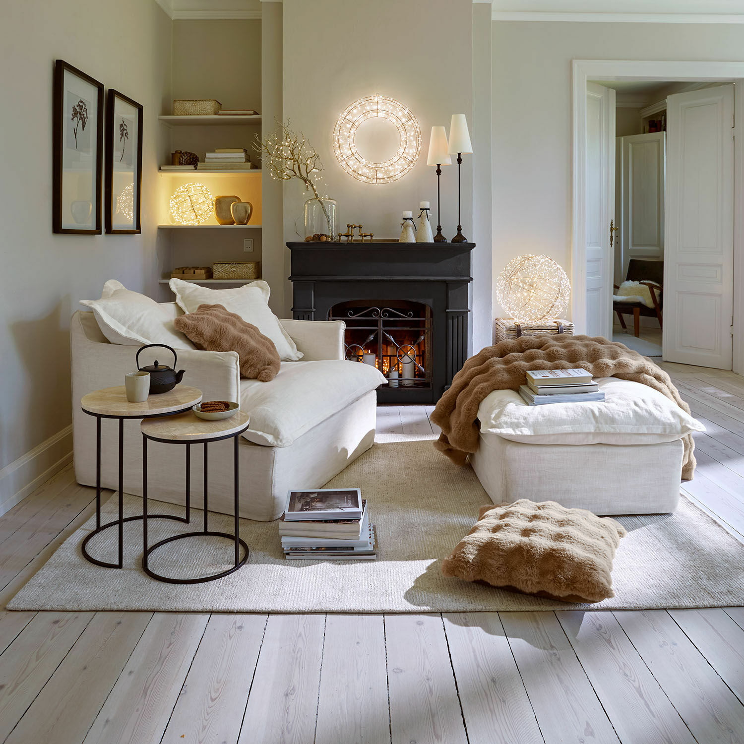 Gezellige woonkamer met crèmekleurige bank en poef, beige kussens en zachte deken, moderne LED-verlichting