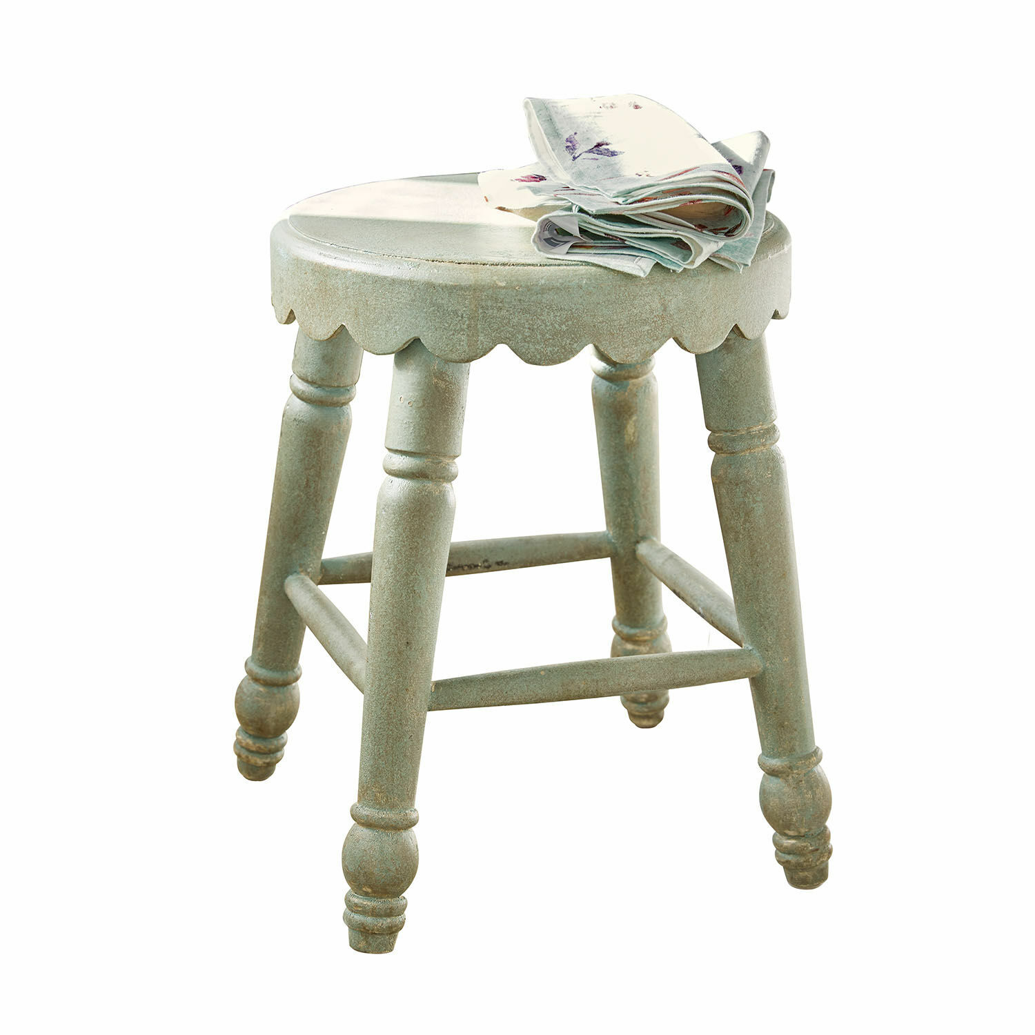 Ronde groene houten kruk met decoratieve rand en gevouwen stof op het zitvlak