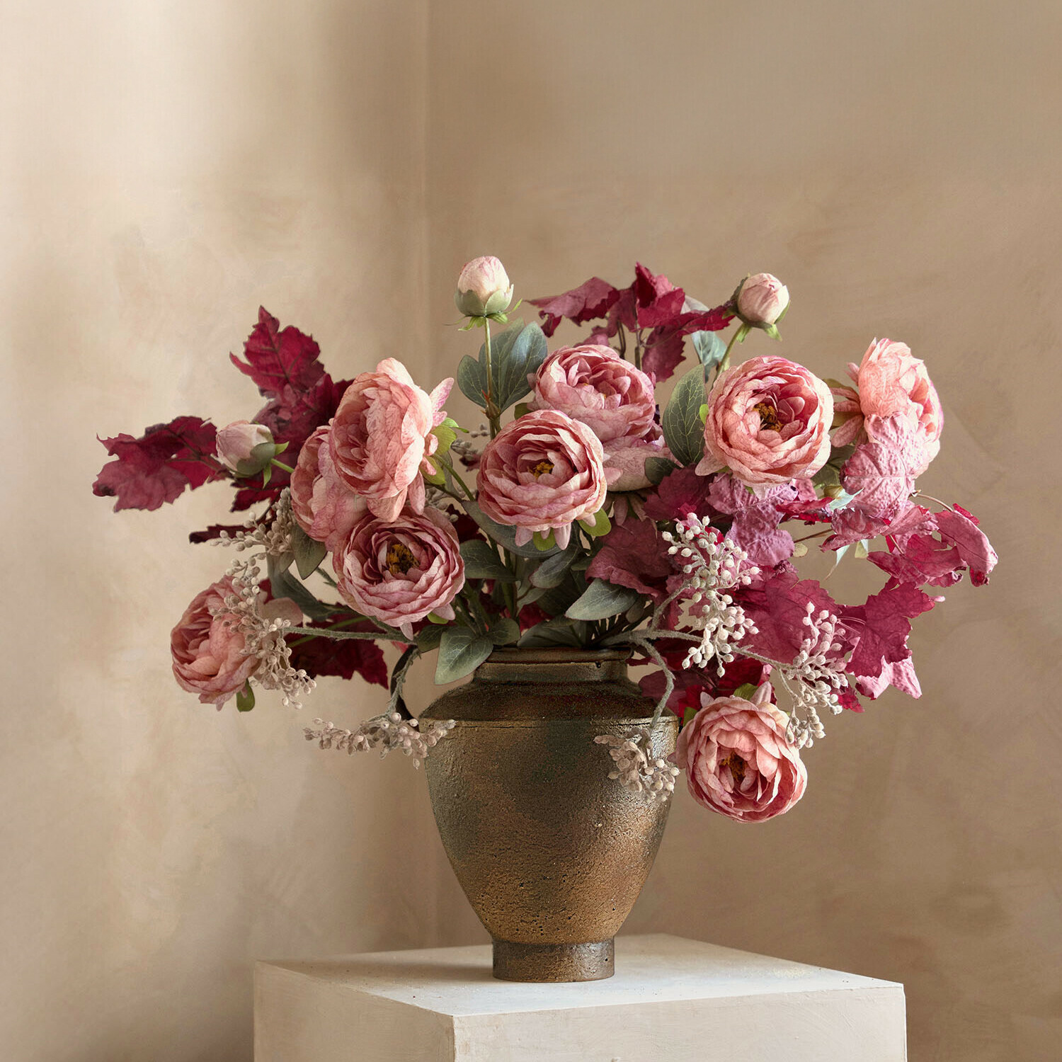 Boeket van roze rozen en rode bladeren in bruine keramische vaas op lichte achtergrond