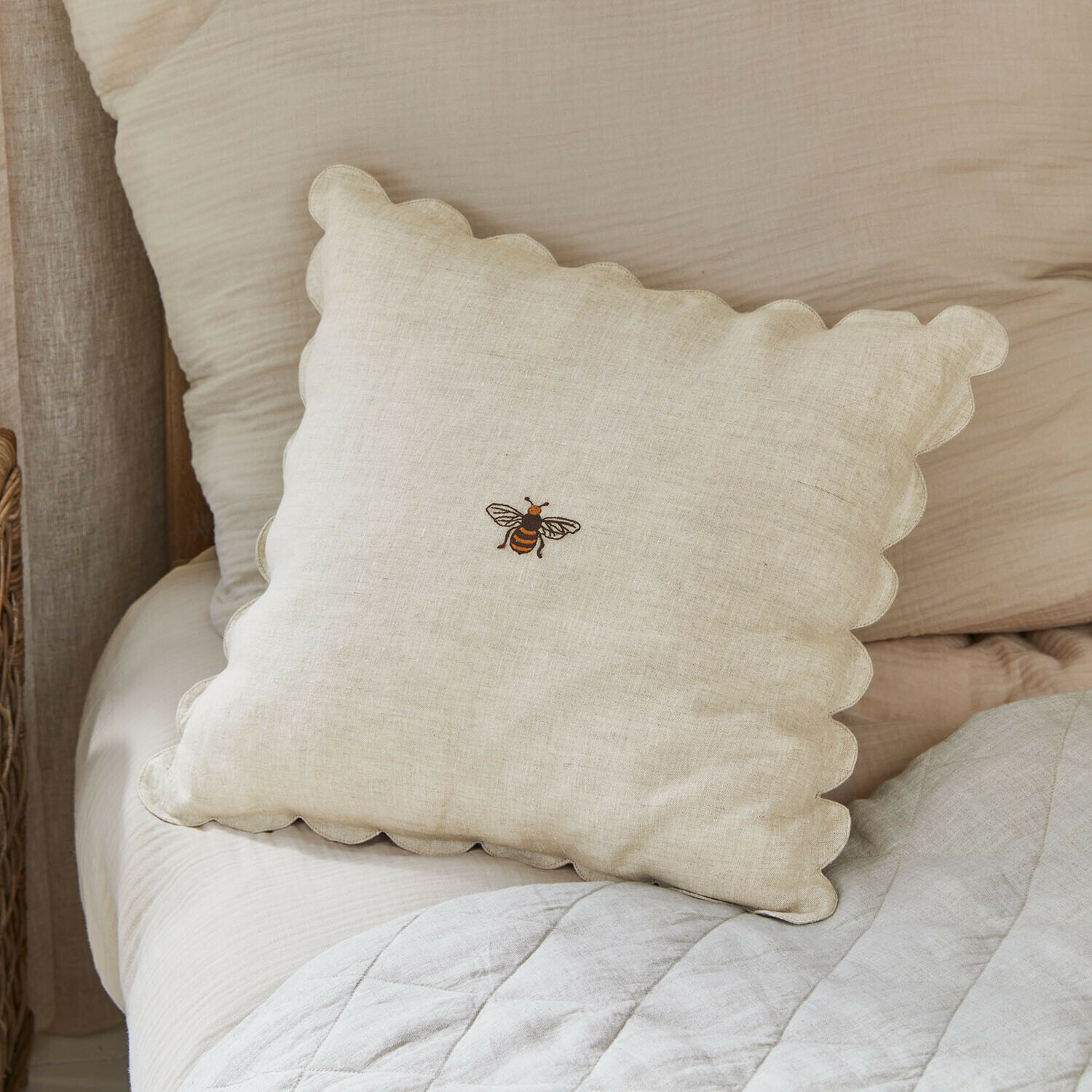 Beige linnen kussen met golvende rand en geborduurde bij, slaapkamerdecoratie