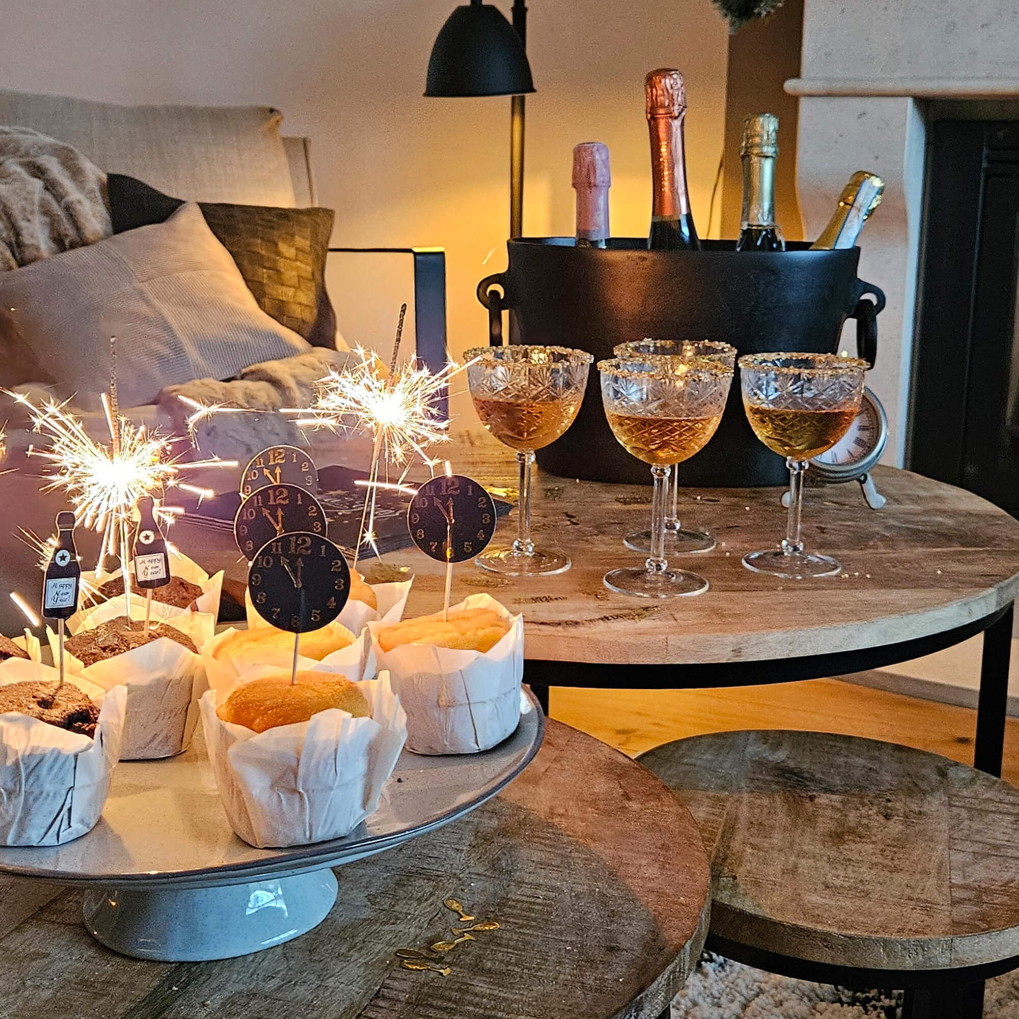 Feest met muffins, glazen en flessen in emmer op houten tafel in gezellige kamer