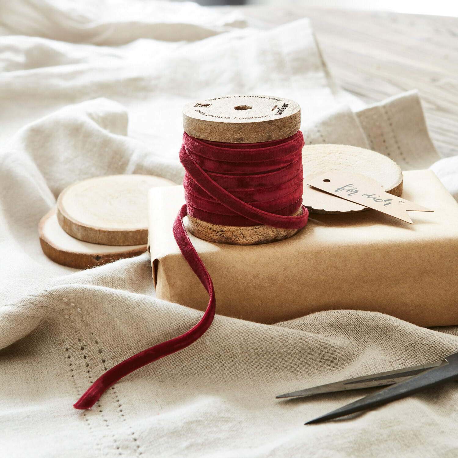 Fluwelen lint Olessa Rode fluwelen lint op houten klos met natuurlijk kraftpapier en schaar voor cadeauverpakking