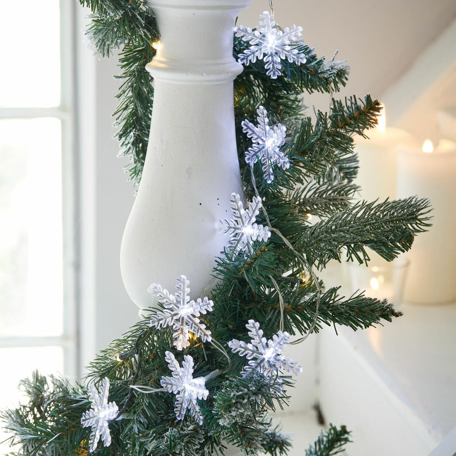 Lichtsnoer met witte sneeuwvlokken aan groene kunstdennenkrans, kerstdecoratie