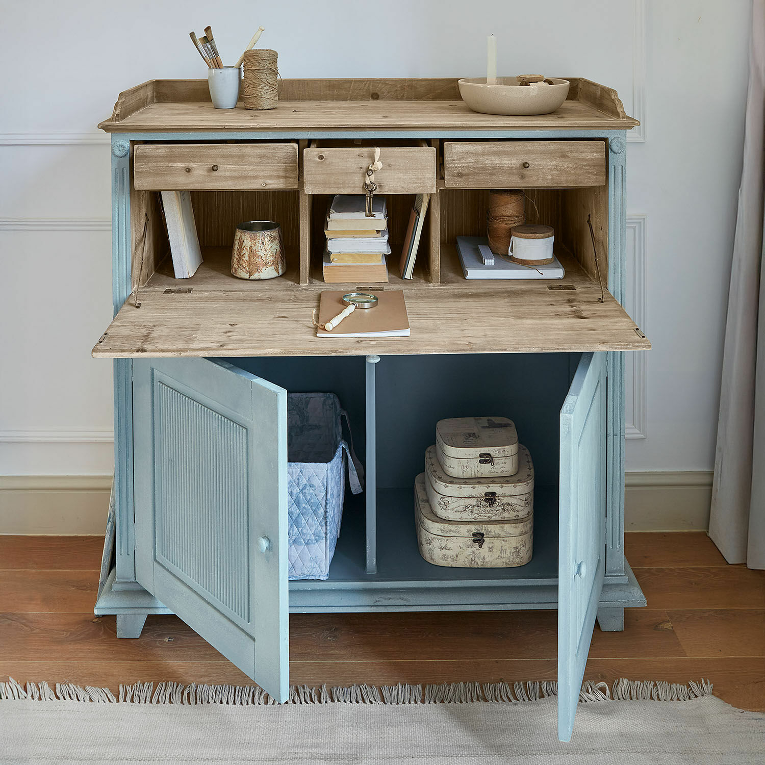 Blauwe houten secretaire met natuurlijk blad en open lades voor georganiseerde opslag