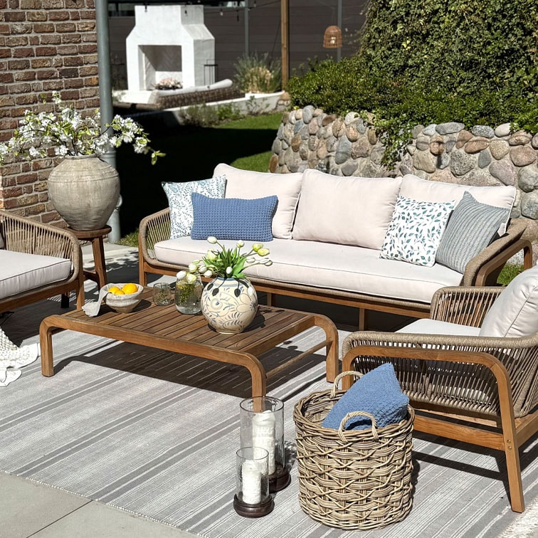 Tuinmeubelset met houten tafel en beige bank met kussens, decoratie op zonnig terras
