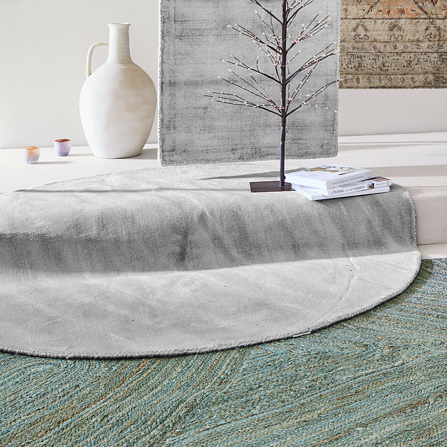 Ronde grijze vloerkleed van zacht materiaal met decoratieve vaas en boeken in een moderne ruimte