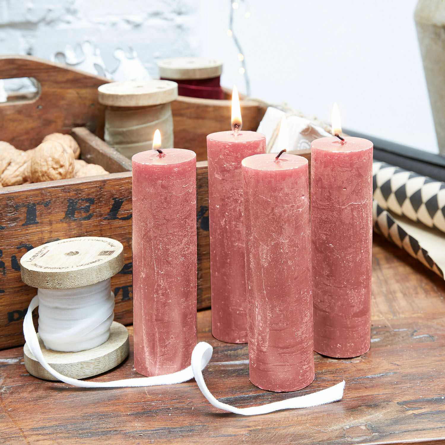 Kaars set van 4 Muriel Vier roze kaarsen van was op houten tafel met decoratief lint en noten