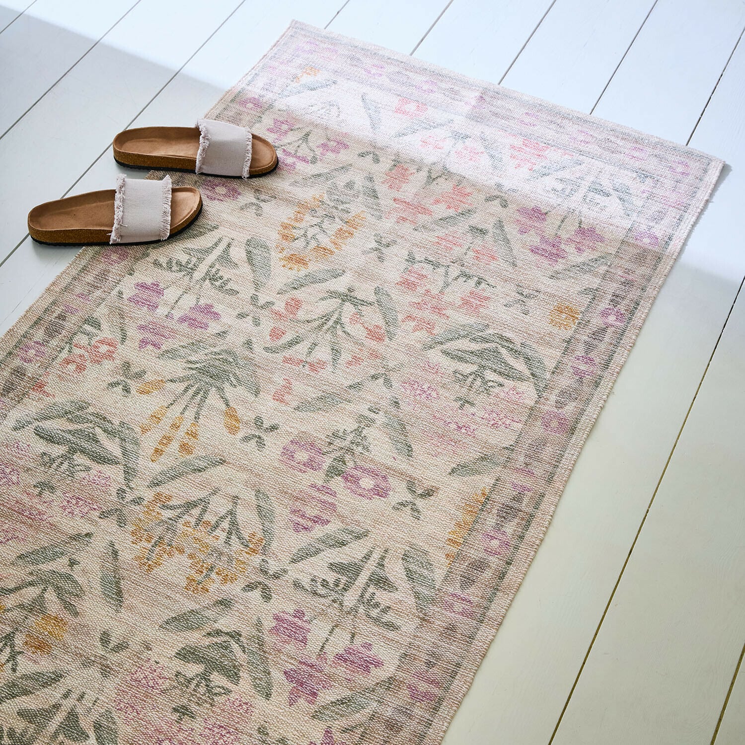 Loper Jardin d'Été Vloerkleed met zacht bloemenpatroon in pasteltinten op lichte vloer met beige slippers