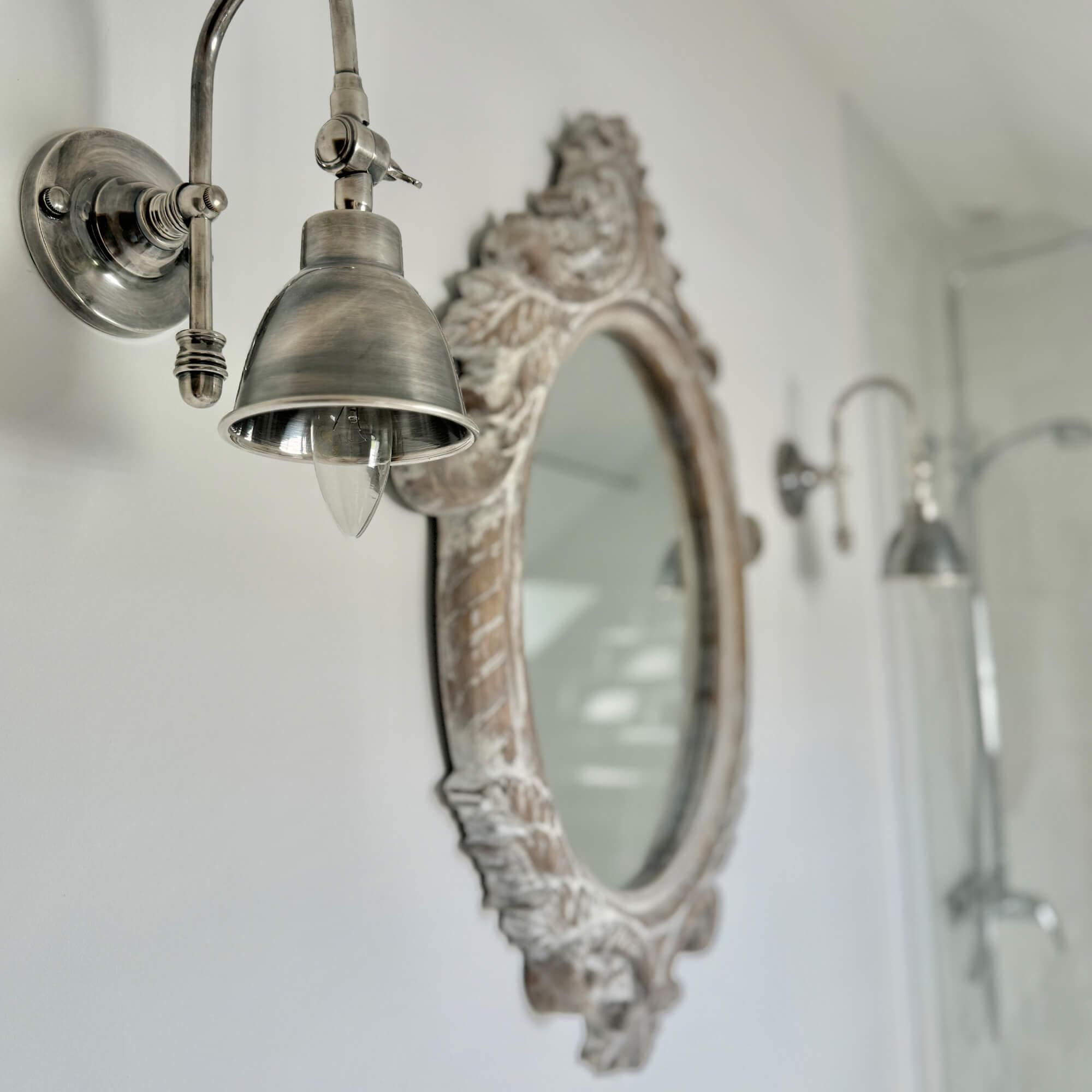 Vintage metalen wandlamp naast decoratieve spiegel in badkamer