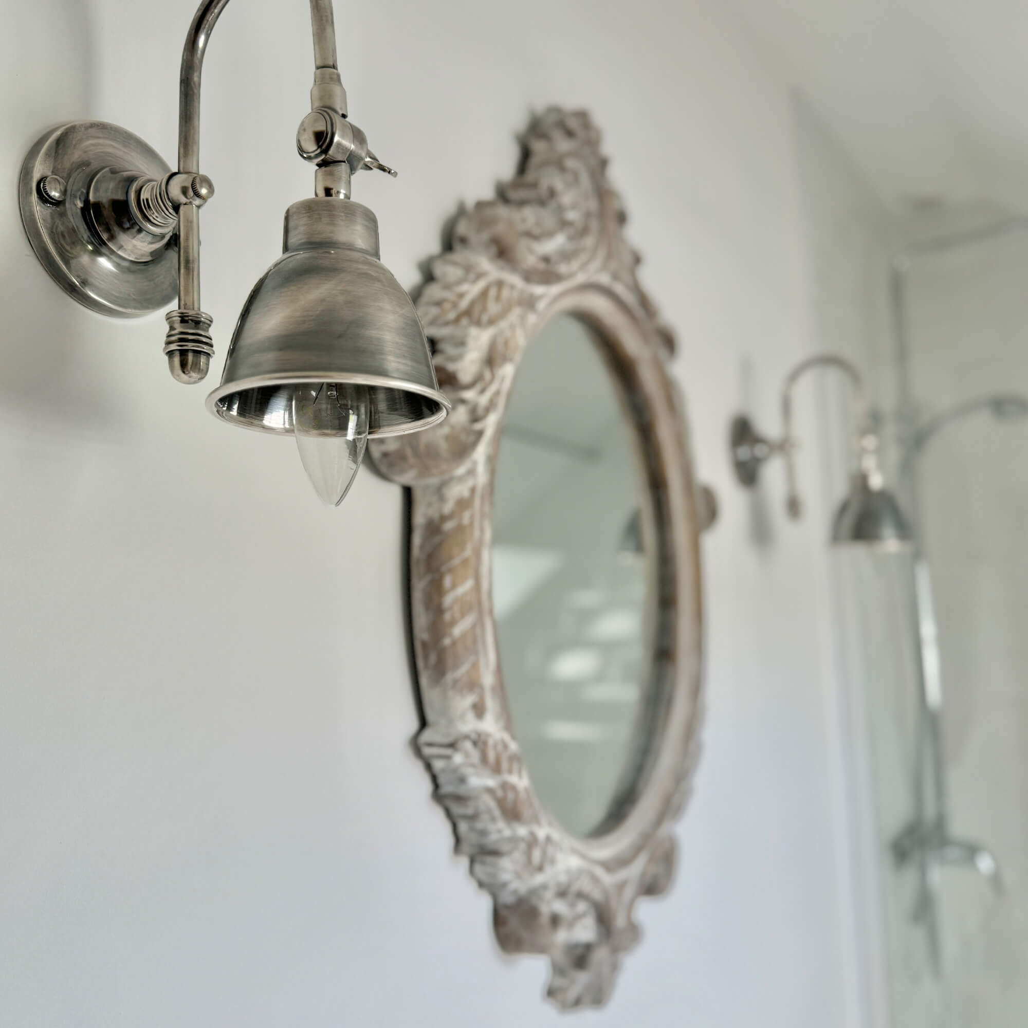Vintage metalen wandlamp naast decoratieve spiegel in badkamer