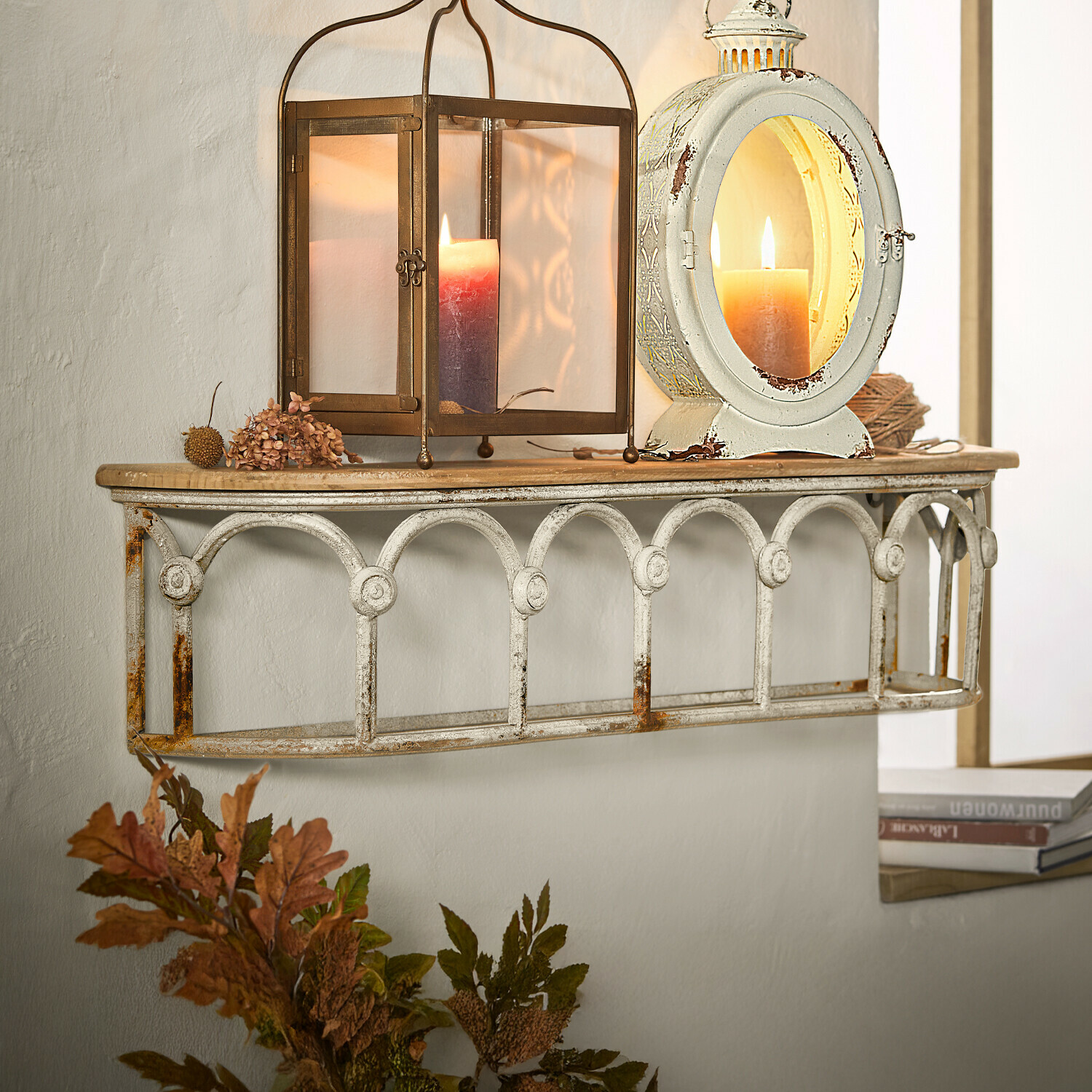 Wandplank van metaal met witte patina en houten blad, versierd met lantaarns en kaarsen voor sfeervolle uitstraling