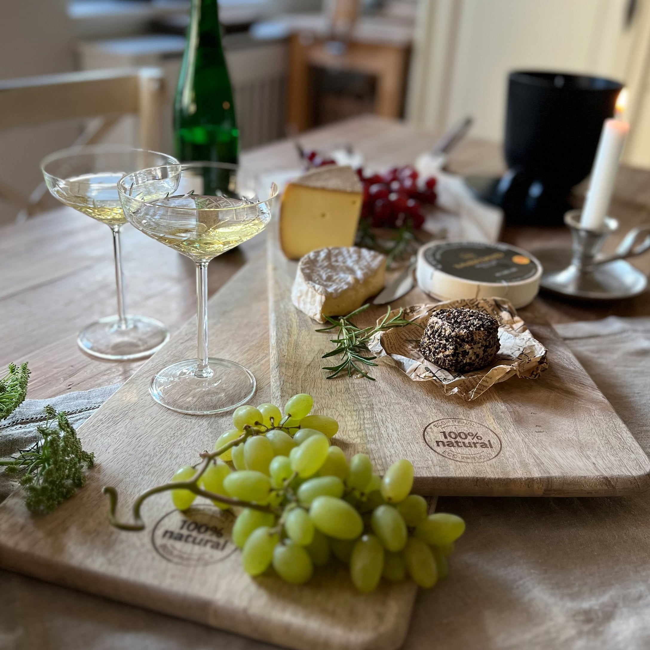 Snijplank van natuurlijk hout met druiven, verschillende kazen en wijnglazen op houten tafel