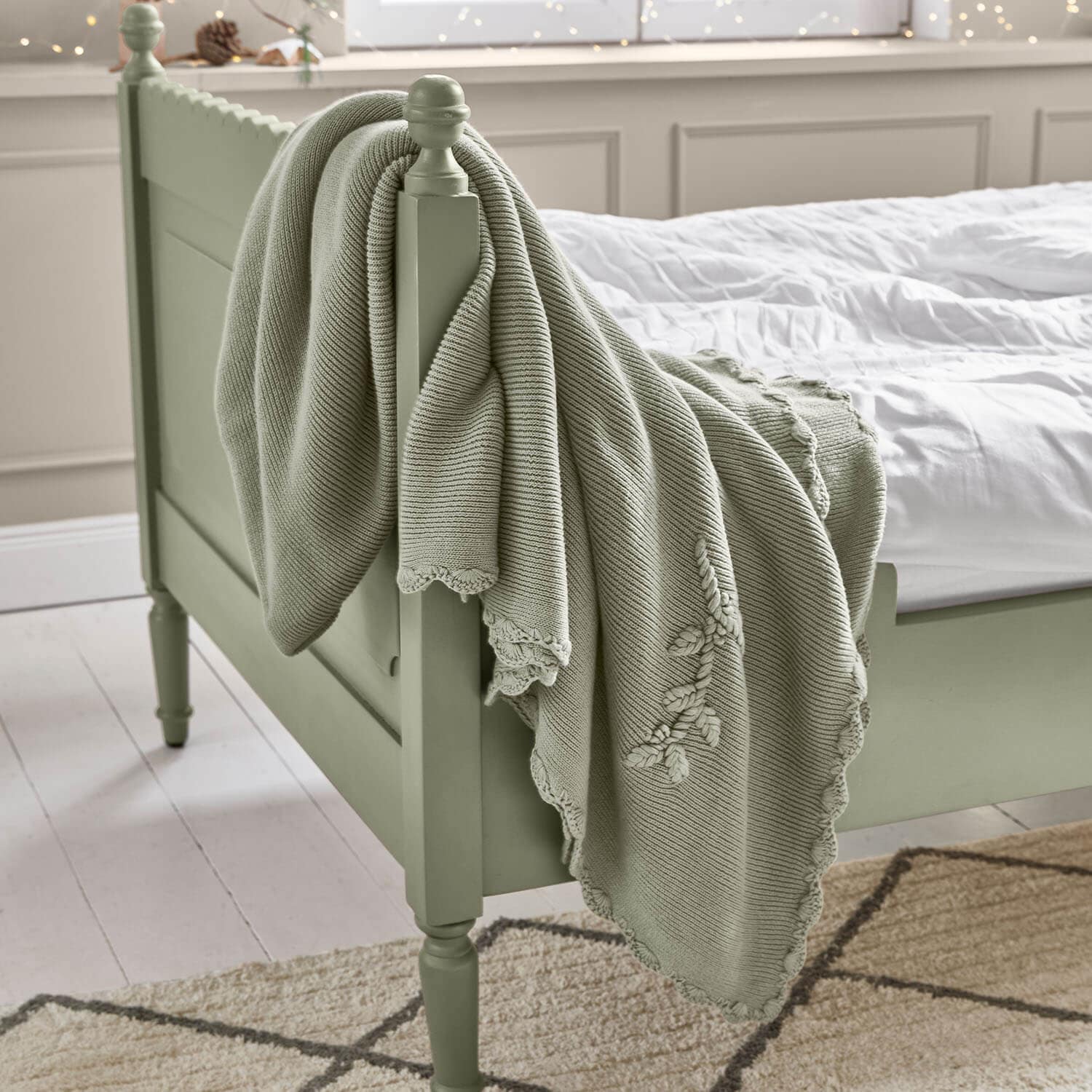Mintgroene katoenen deken met decoratief borduurwerk op een houten bed in slaapkamer